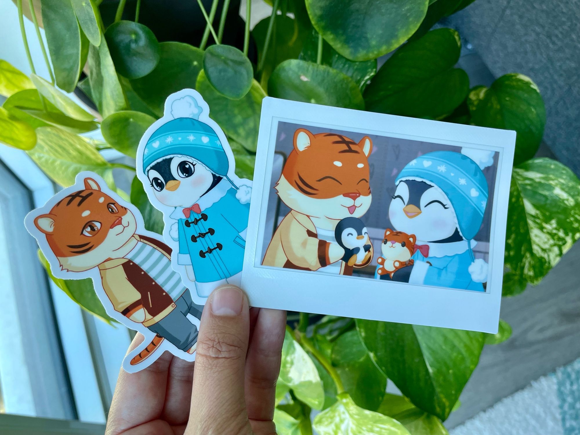 Me holding a polaroid of Apollo and Wobbles, a sticker of Apollo, and a sticker of Wobbles