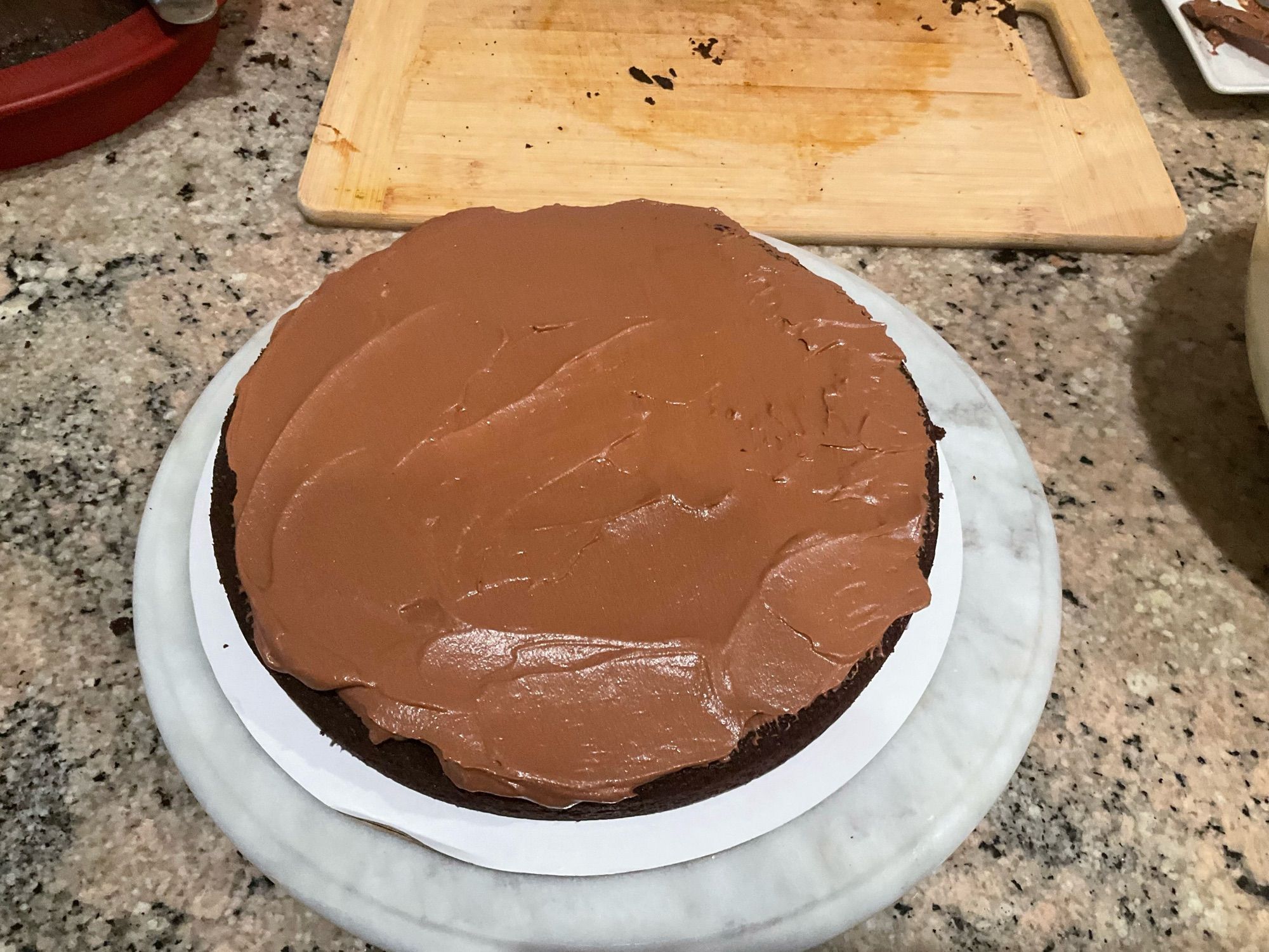 The bottom layer of a dark chocolate layer cake. It has dark chocolate mousse spread on top of the layer.