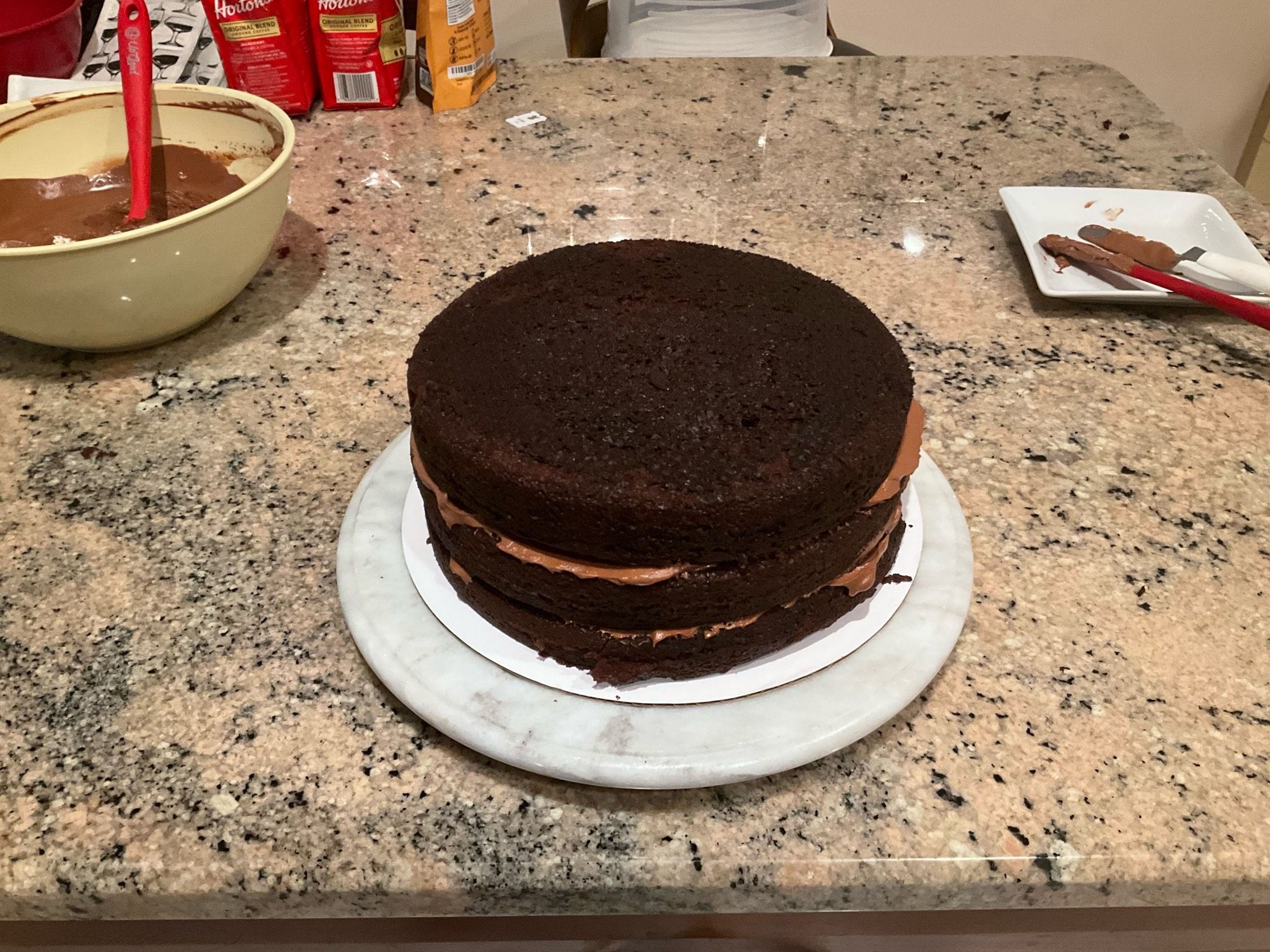 A dark chocolate cake with all theee layers stacked in place. There is dark chocolate mouse between the layers.