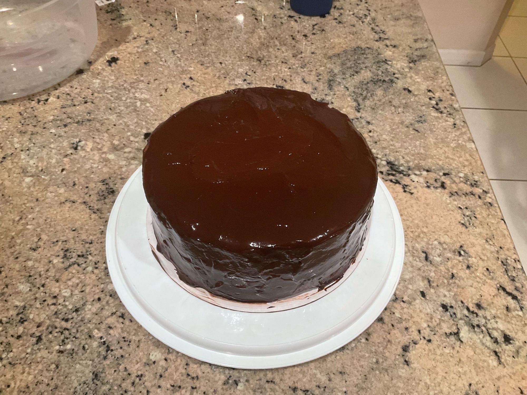 A completed dark chocolate layer cake. It is covered in dark chocolate ganache over a layer of dark chocolate mousse. The mousse is not visible.