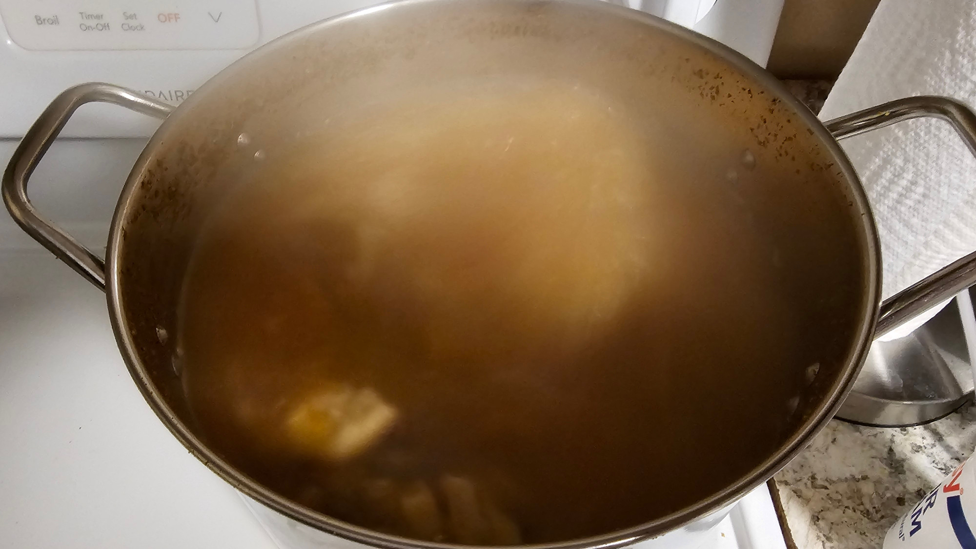 A 12-quart pot is nearly filled to the handles with steamy soup.