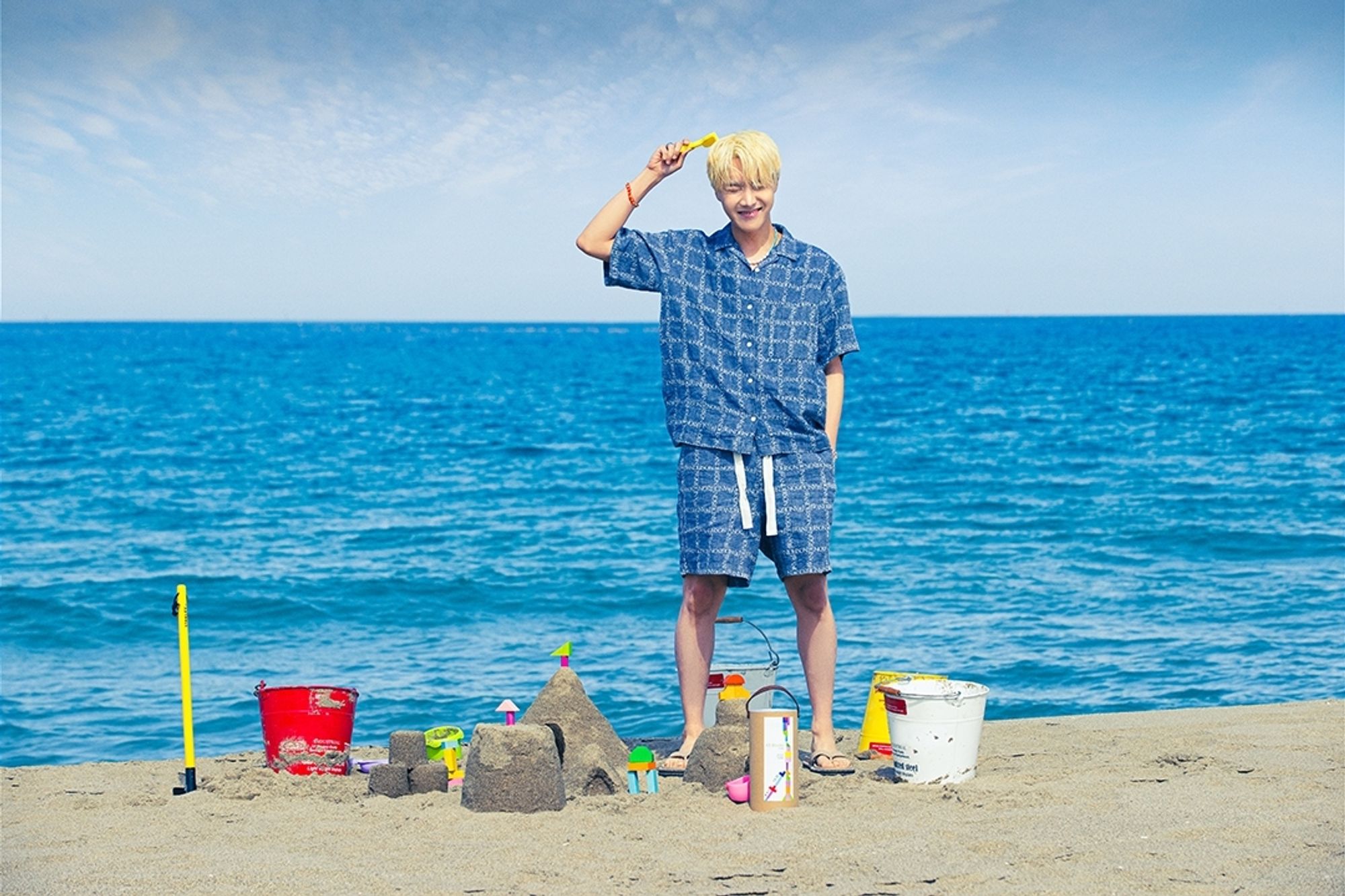 Hobi standing on a beach in what look like blue pyjamas.