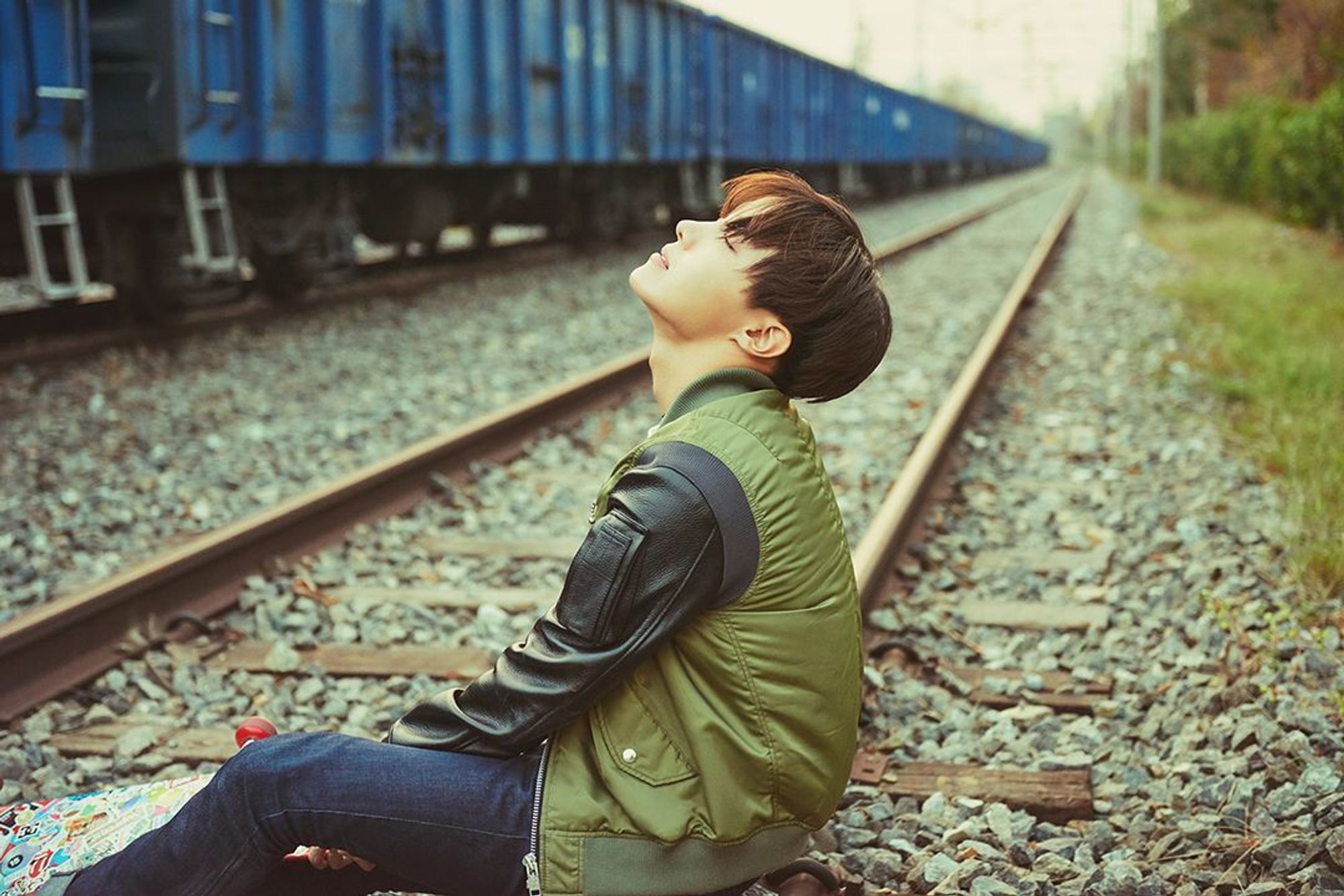 Hobi sitting on a train track, looking up at the sky