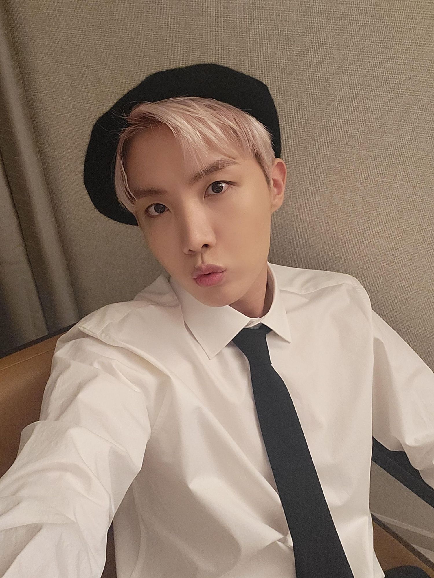 Hobi making a kissy face at the camera. He's got blond hair, hidden under a hat.