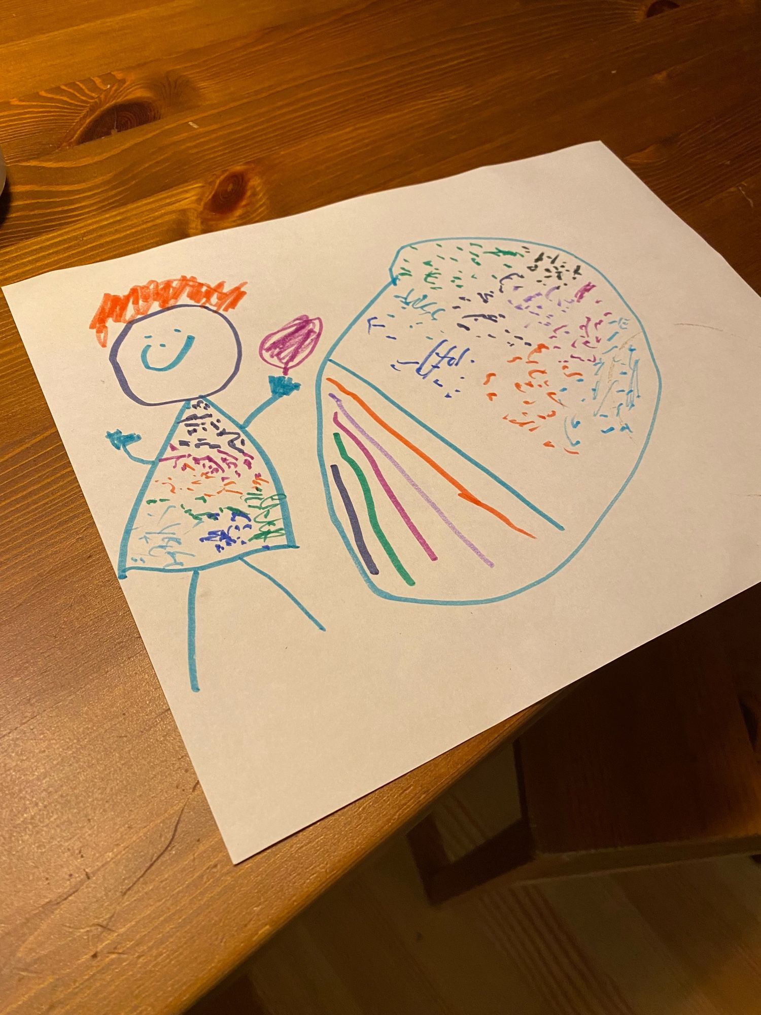 A drawing of me by my four year old, cooking friend rice. I have orange hair, a sparkling rainbow apron, a purple spatula and the wok is the same size as me.