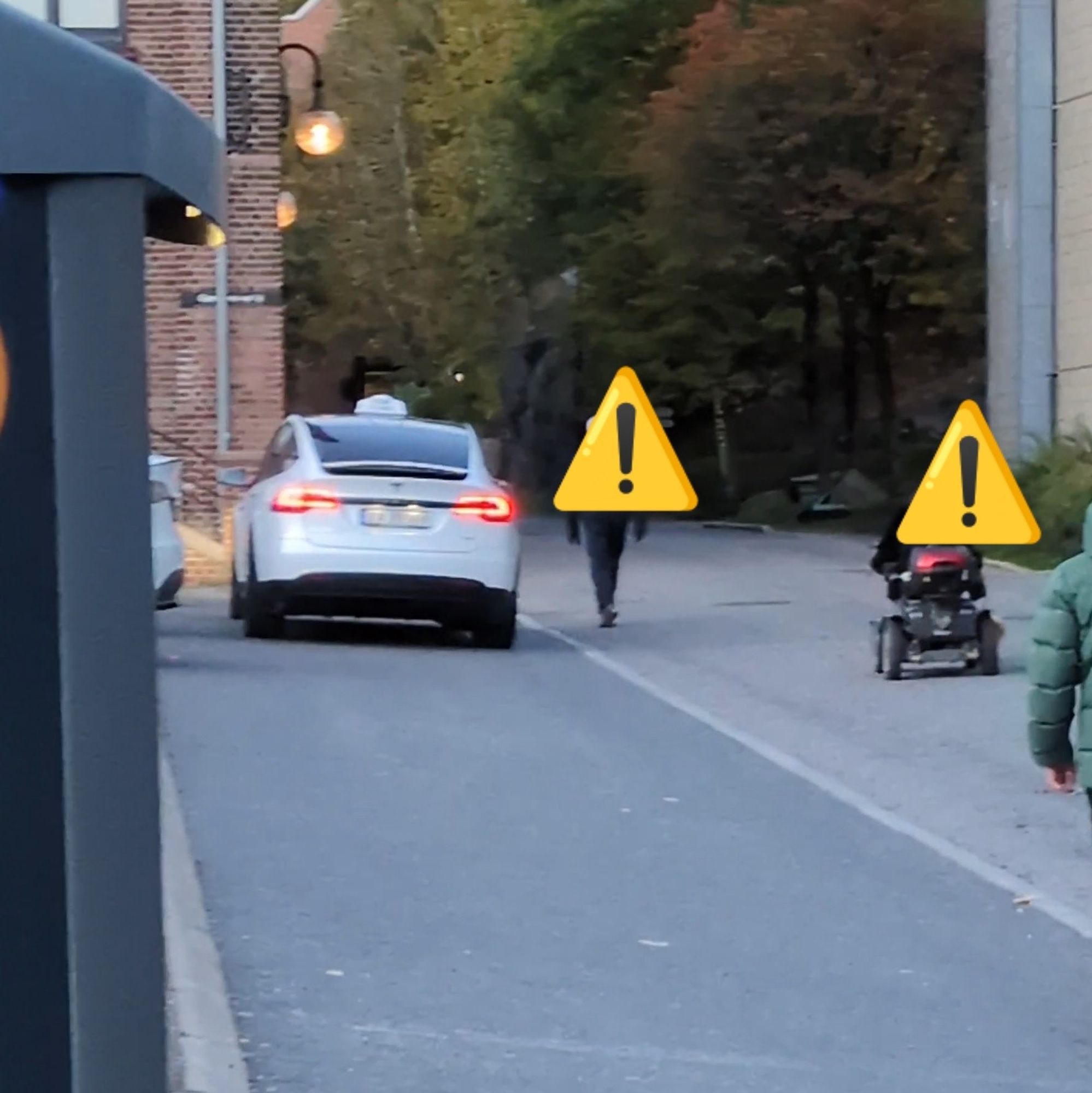 White taxi taking up whole pavement and two pavement users forced out into the road