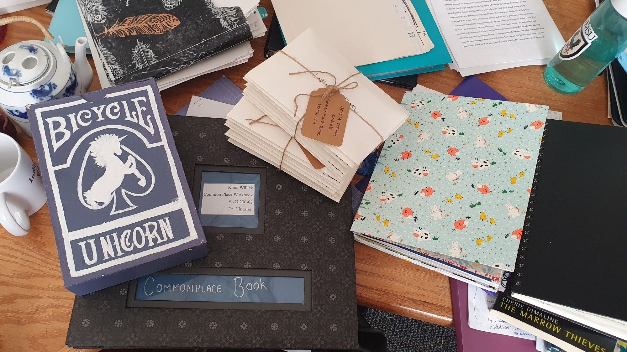 An image of a big, black scrap book, a pile of letters tied together, a large box painted to look like a box of cards, and a scrapbook with a colourful bunny-patterned fabric cover