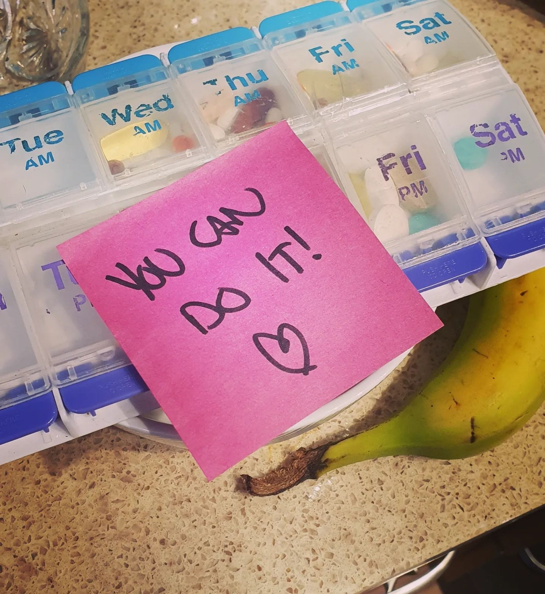 A bright pink post-it saying "You can do it! ❤️" stuck to a pill minder