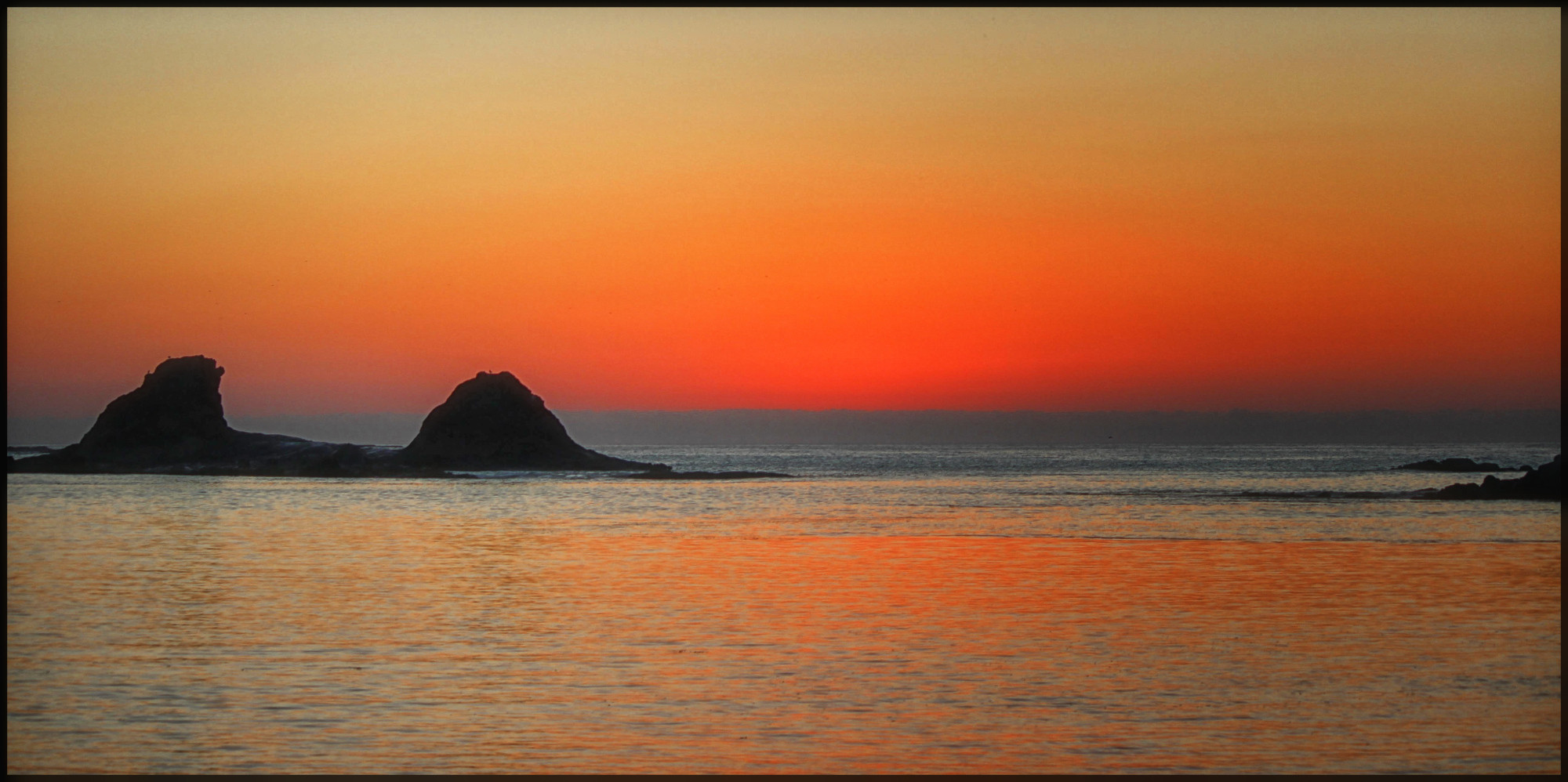 Catching the brilliant colors of a spectacular sunset just after the sun dropped out of sight. It's not easy to describe the variation of the golden hour hues as the smooth ocean picks up the many shades of reflected blue and red as the horizon turns a deep shade of crimson. The sky above still retains a hint of blue mixed with the red glow from the sinking sun. This is the phenomenon that kept me going back again and again to experience this amazing light show.... 