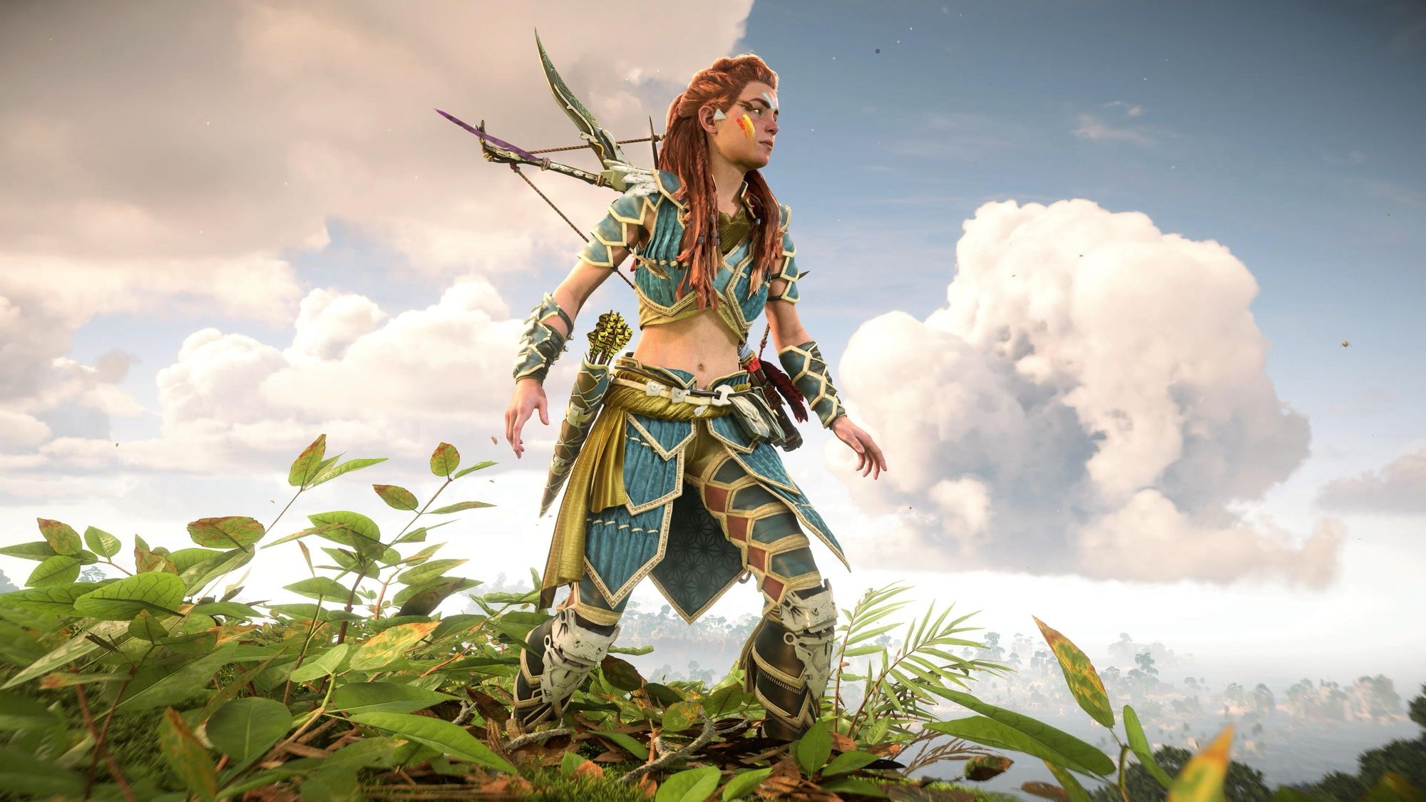 A screenshot of Aloy as she stands on a cliff with clouds behind her.