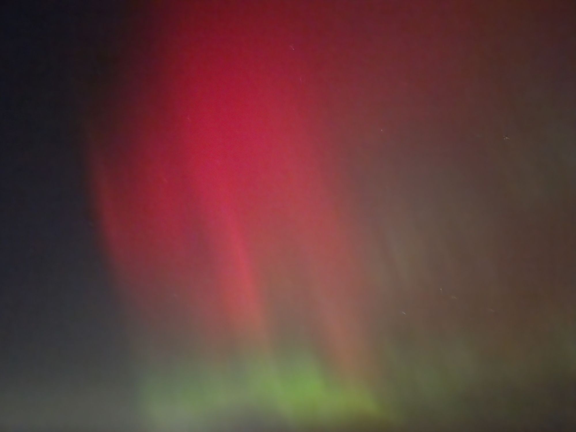 Northern lights, stretching almost overhead, vibrant pink-red over narrower band of green.