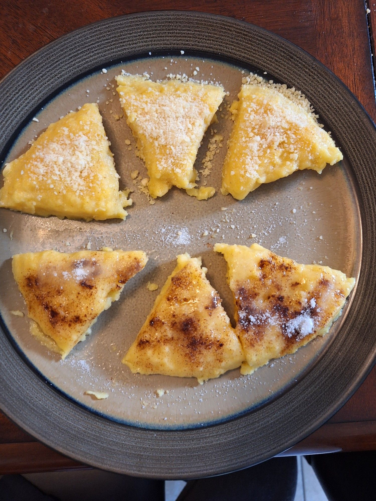 Romanian mamaliga - yellow cornmeal polenta, cut in six slices. Half are covered in cinnamon and sugar, the other half in garlic and parm cheese.