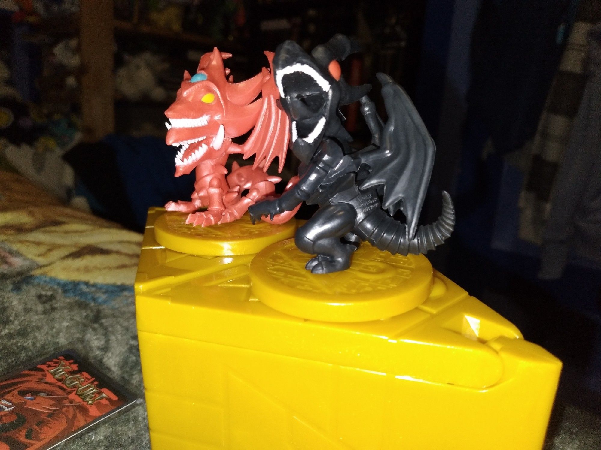 A right side view of a close up of the mini chibi figs of the yugiog characters Slifer the sky dragon and Red-Eyes black dragon.