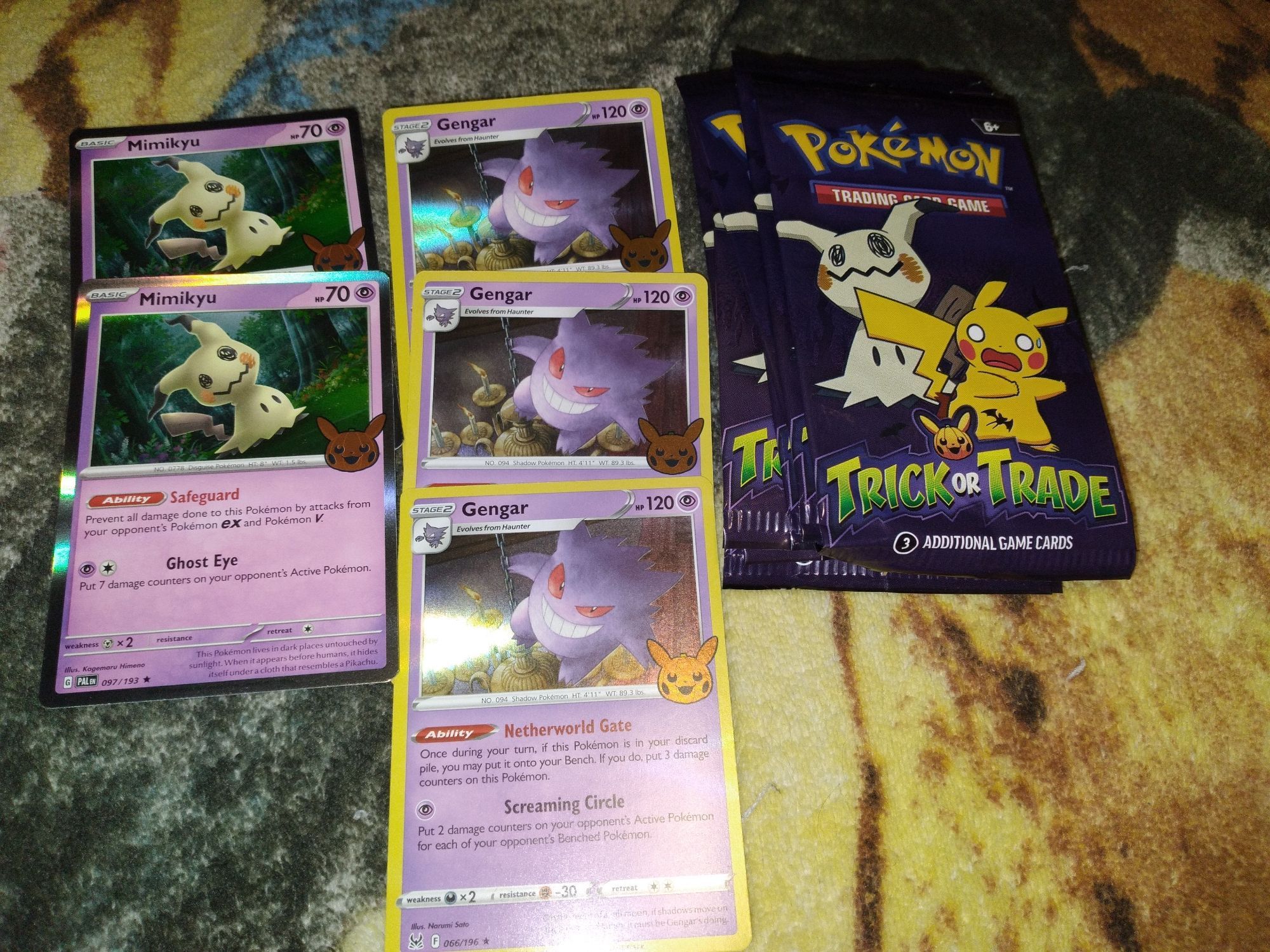 2 purple holo cards on the left with a creepy puppet ghost named Mimikyu and on the right 3 other purple holo cards with a smiley scary ghost named Gengar.