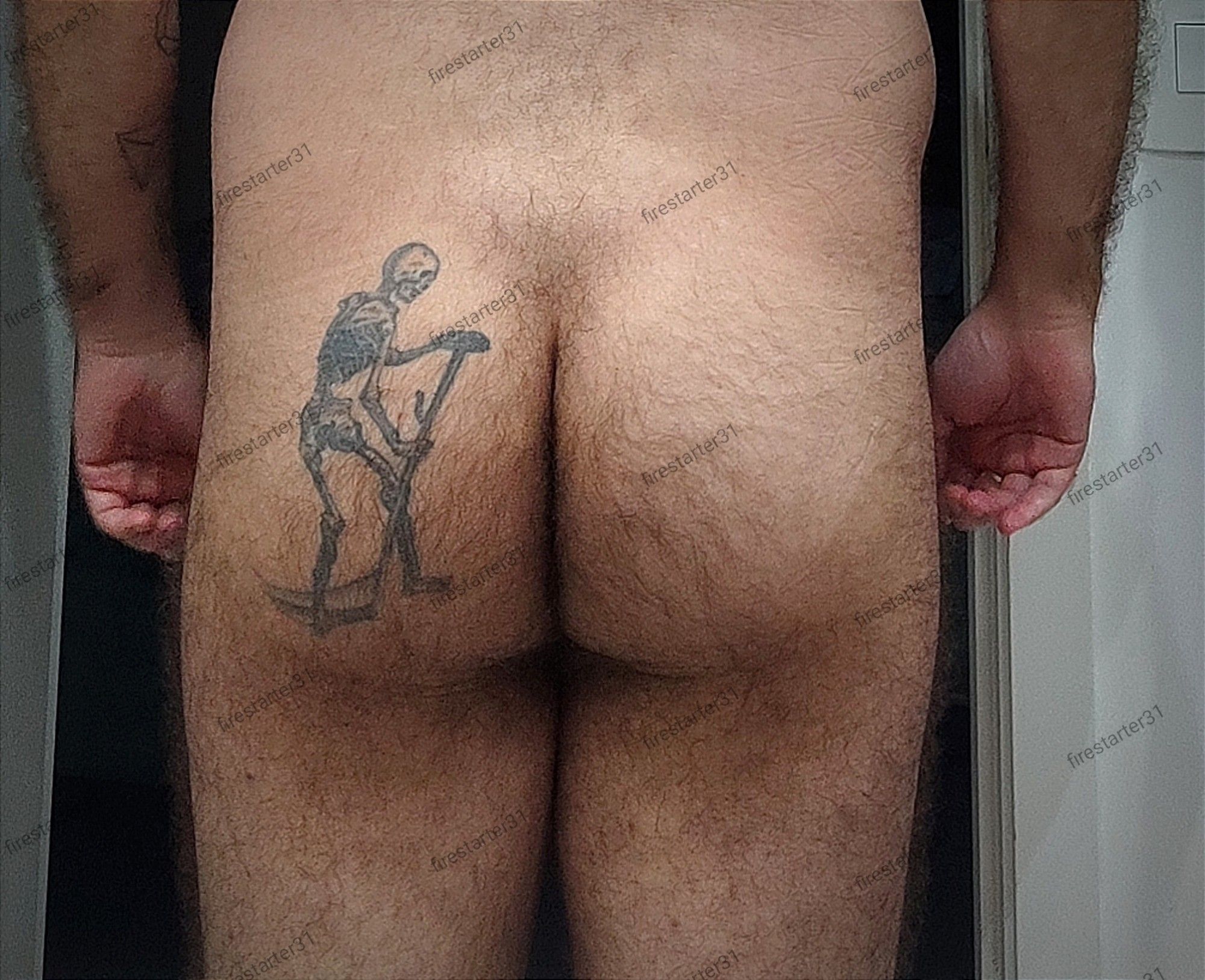 A slightly beefy and hairy ass with a skeleton tattooed to the left bum