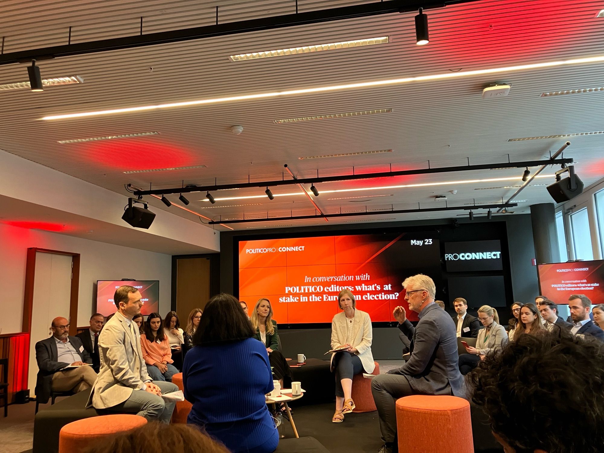 A stage with four editors and a moderator with orange POLITICO PRO CONNECT screens in the background