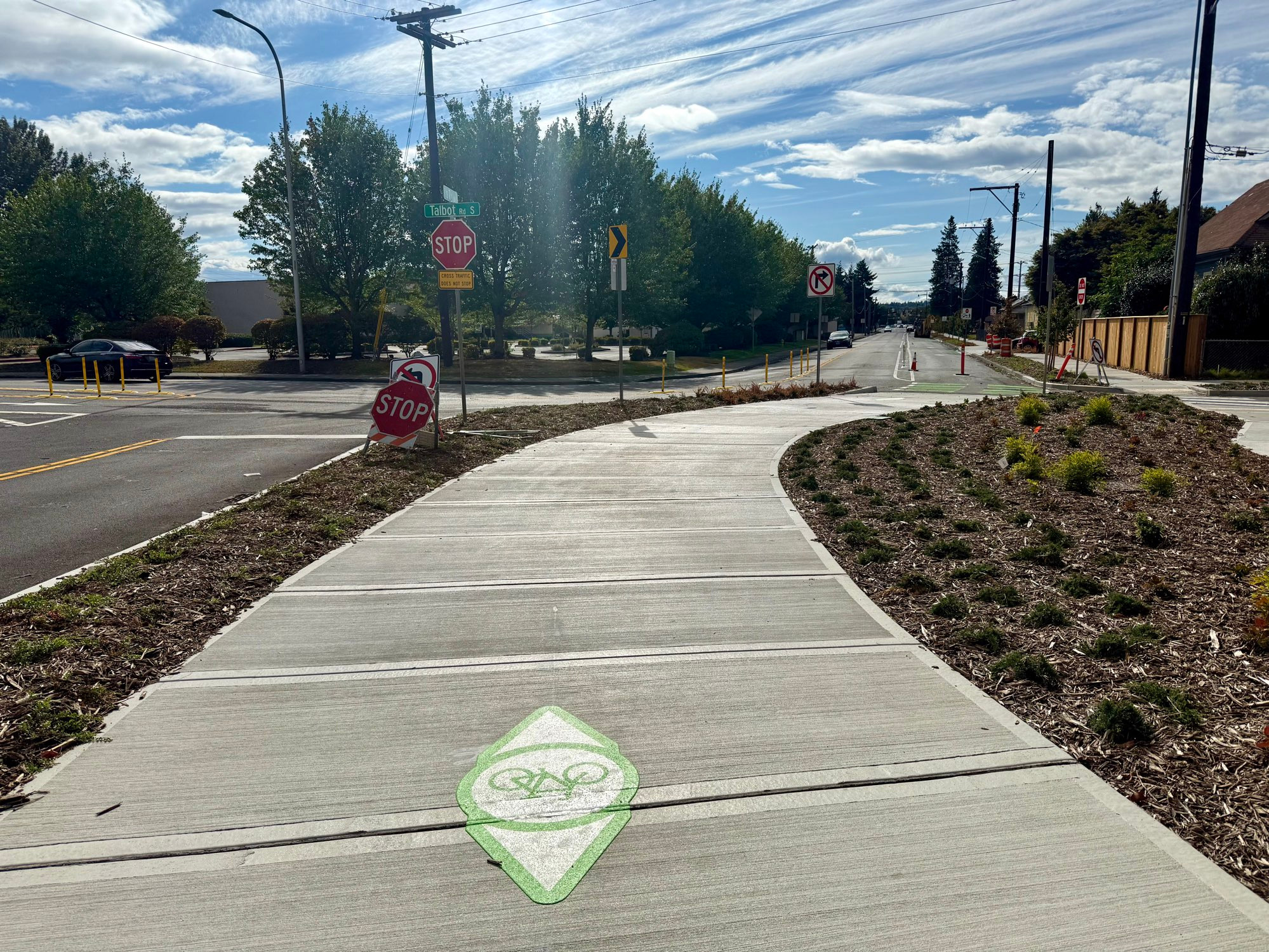 A bicycle symbol sits on a new curving concrete 2-way bike lane 