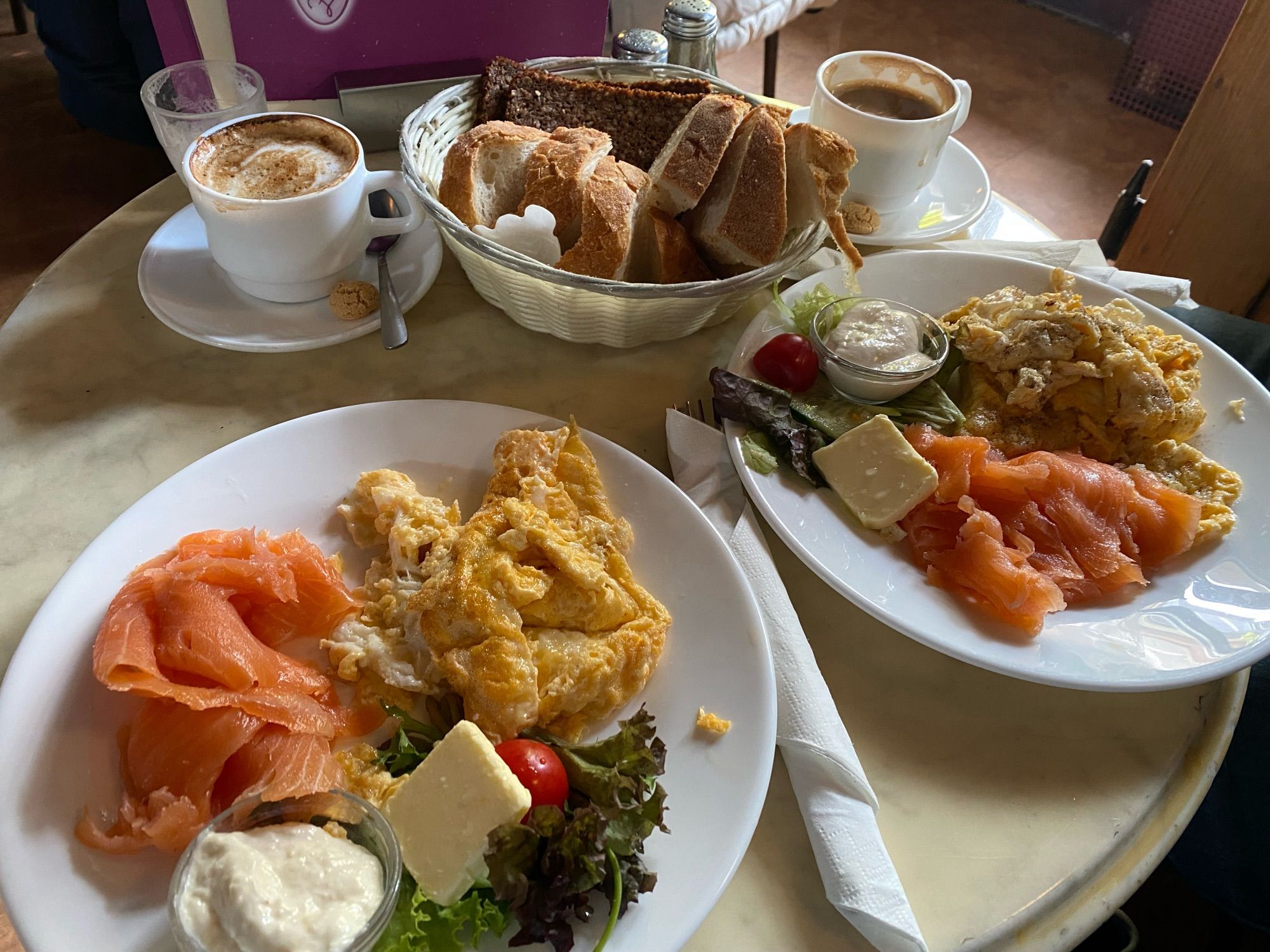 Zwei Teller mit Rührei, Lachsscheiben, Meerrettich, einem kleinen Stück Butter, Salat und einer Cocktail Tomate