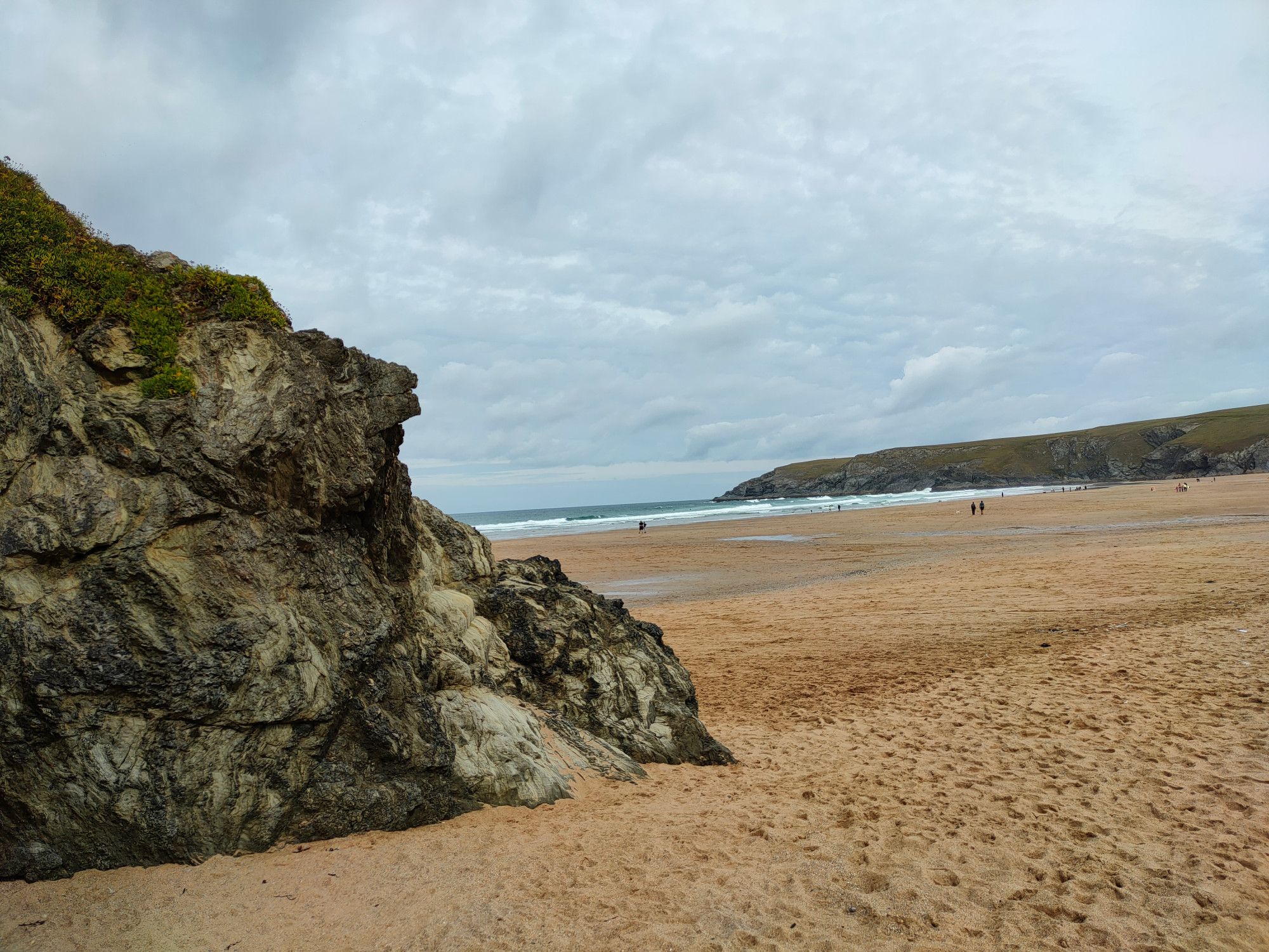 Combination of rugged granite outcrops and sand, cliffs in the distance.