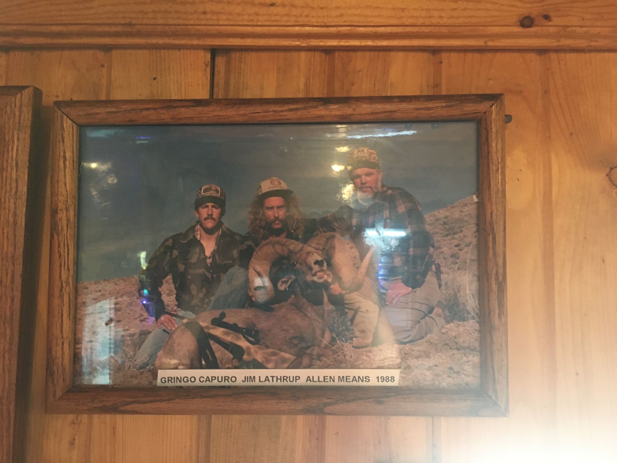 photo from 1988 of three hunters posing with a bighorn sheep. their names are gringo capuro (lol), jim lathrup, and allen means. plaid attired, glorious facial hair on all and a hell of a mane of hair on lathrup