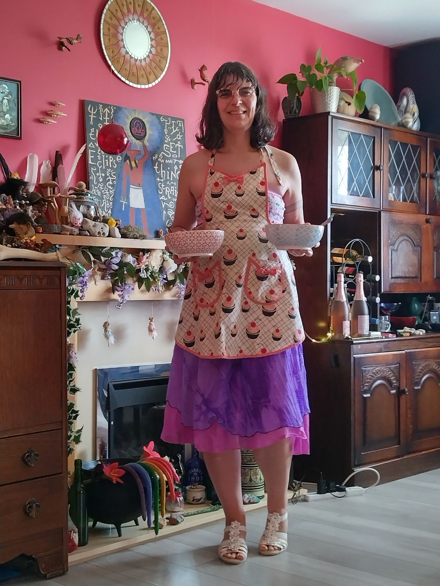 Me in white sandles, a pink and purple skirt, and a cute apron with cupcakes all over hold two bowls.