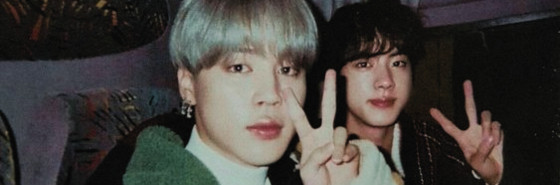 Park Jimin and Kim Seokjin holding up peace signs at the camera.