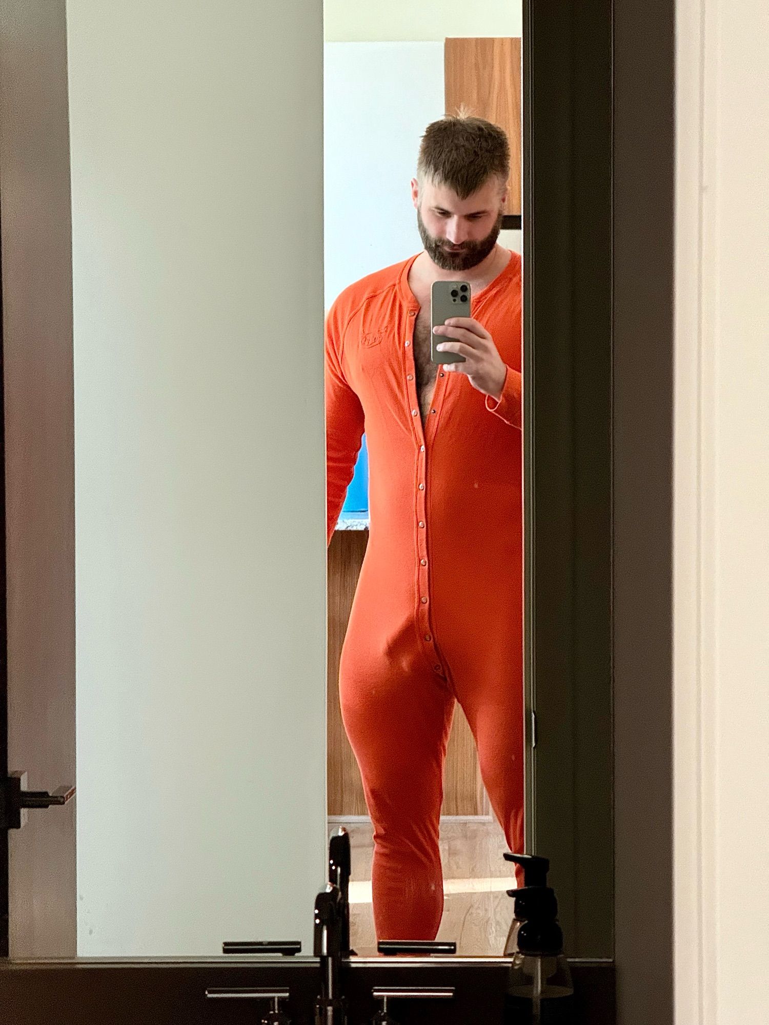 Mirror selfie, wearing a bulgy orange union suit.