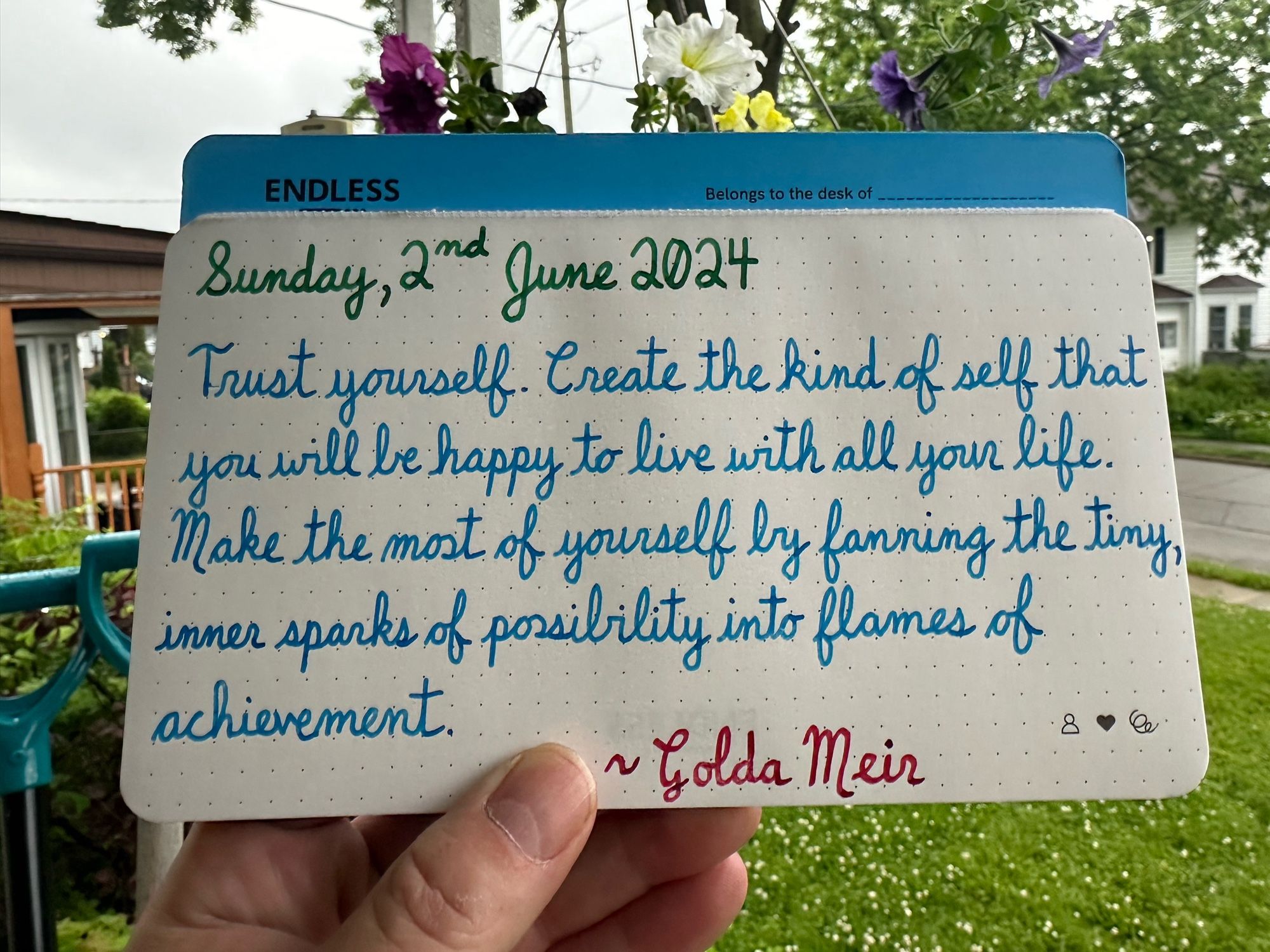 A pen quote of Gilda Meir that reads, “Trust yourself. Create the kind of self that you will be happy to live with all your life. Make the most of yourself by fanning the tiny, inner sparks of possibility into flames of achievement.”

Written in Pelikan Edelstein Adventurine & Topaz, along with Wearingeul Captain Hook.

Hanging plant was made for me by my sister with a non-binary theme. 💛🤍💜🖤