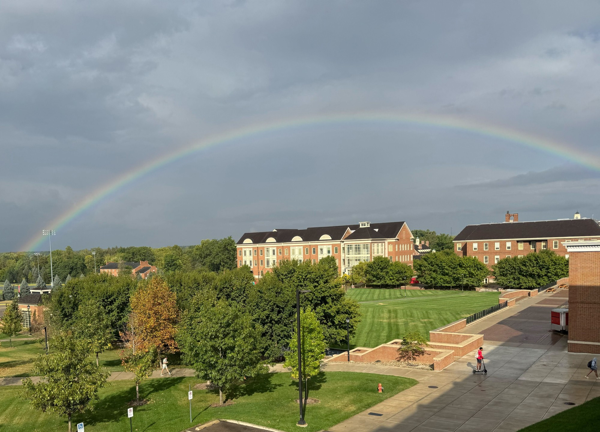 A rainbow stretching over the psychology building on a beautiful tree lined college campus