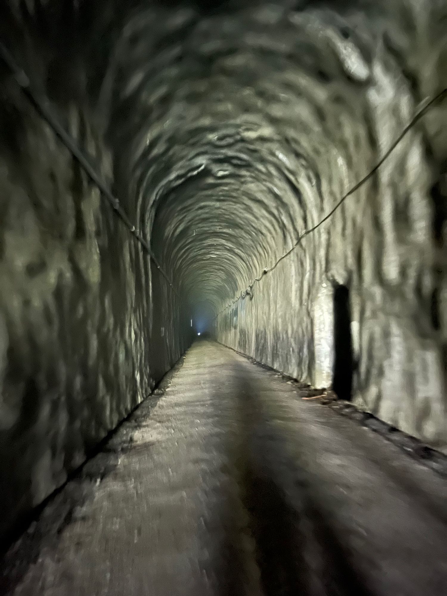 strange partially out of focus pic of the inside of an abandoned railway tunnel, very beige with a dot of light at the end 