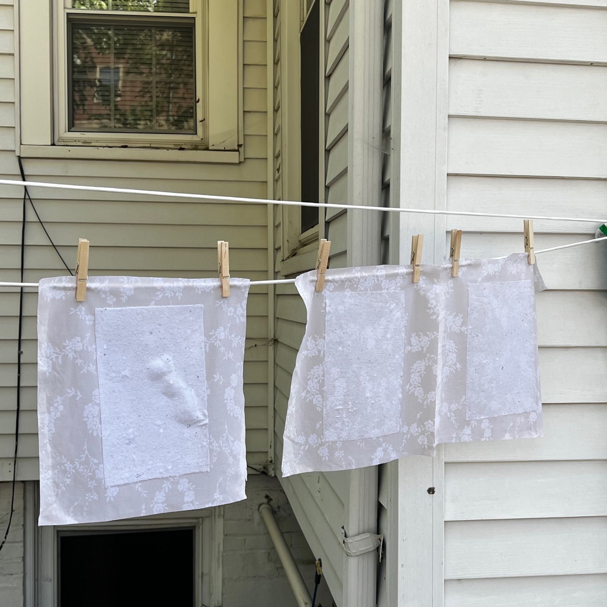 three sheets of paper drying on a clothesline