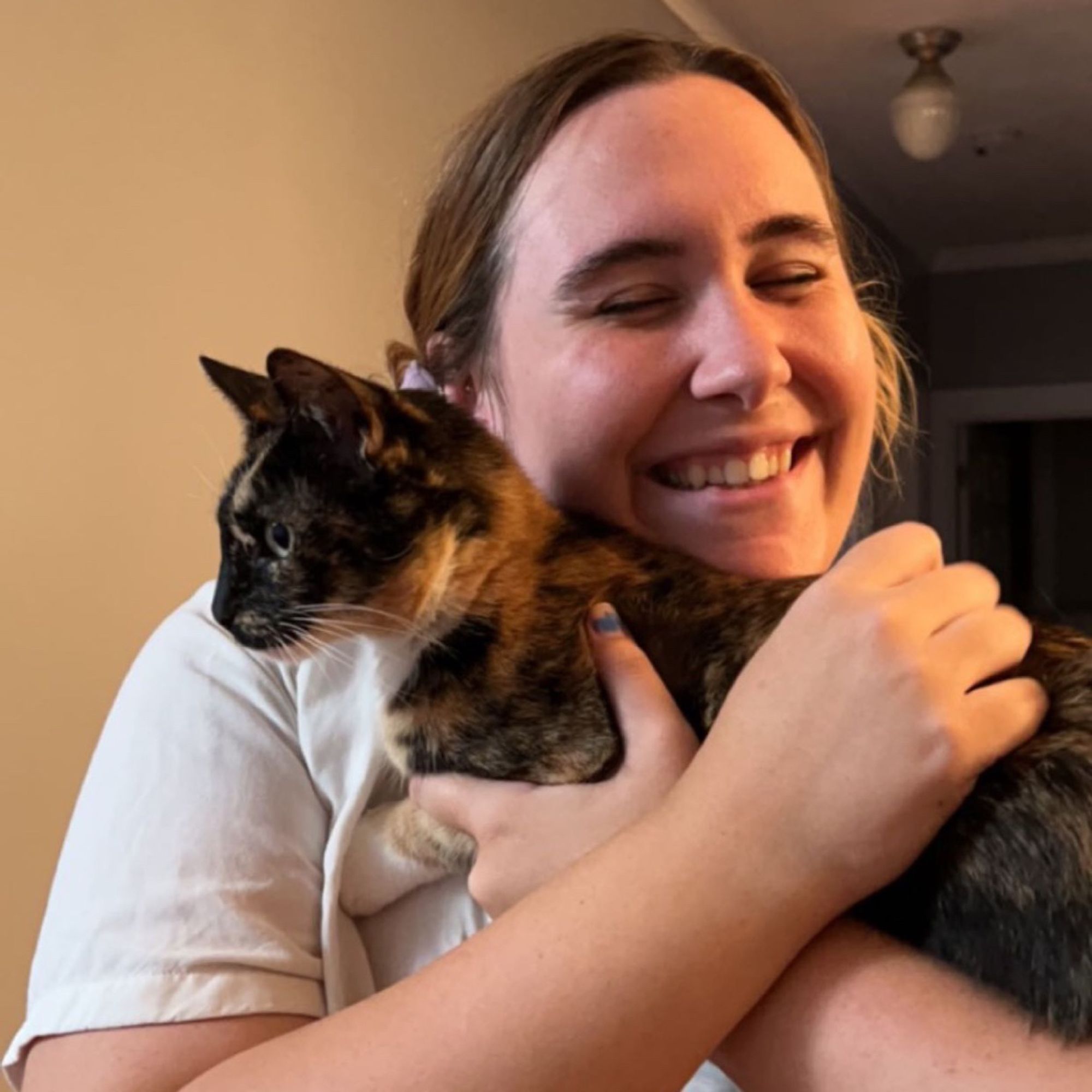 liz smiling, hugging a tiny tortoiseshell cat