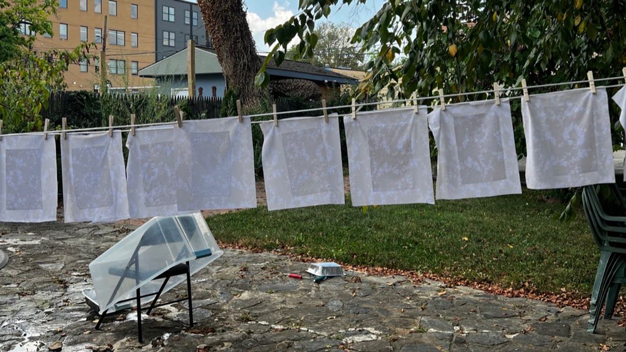 hanging sheets of drying paper on a clothesline in a backyard