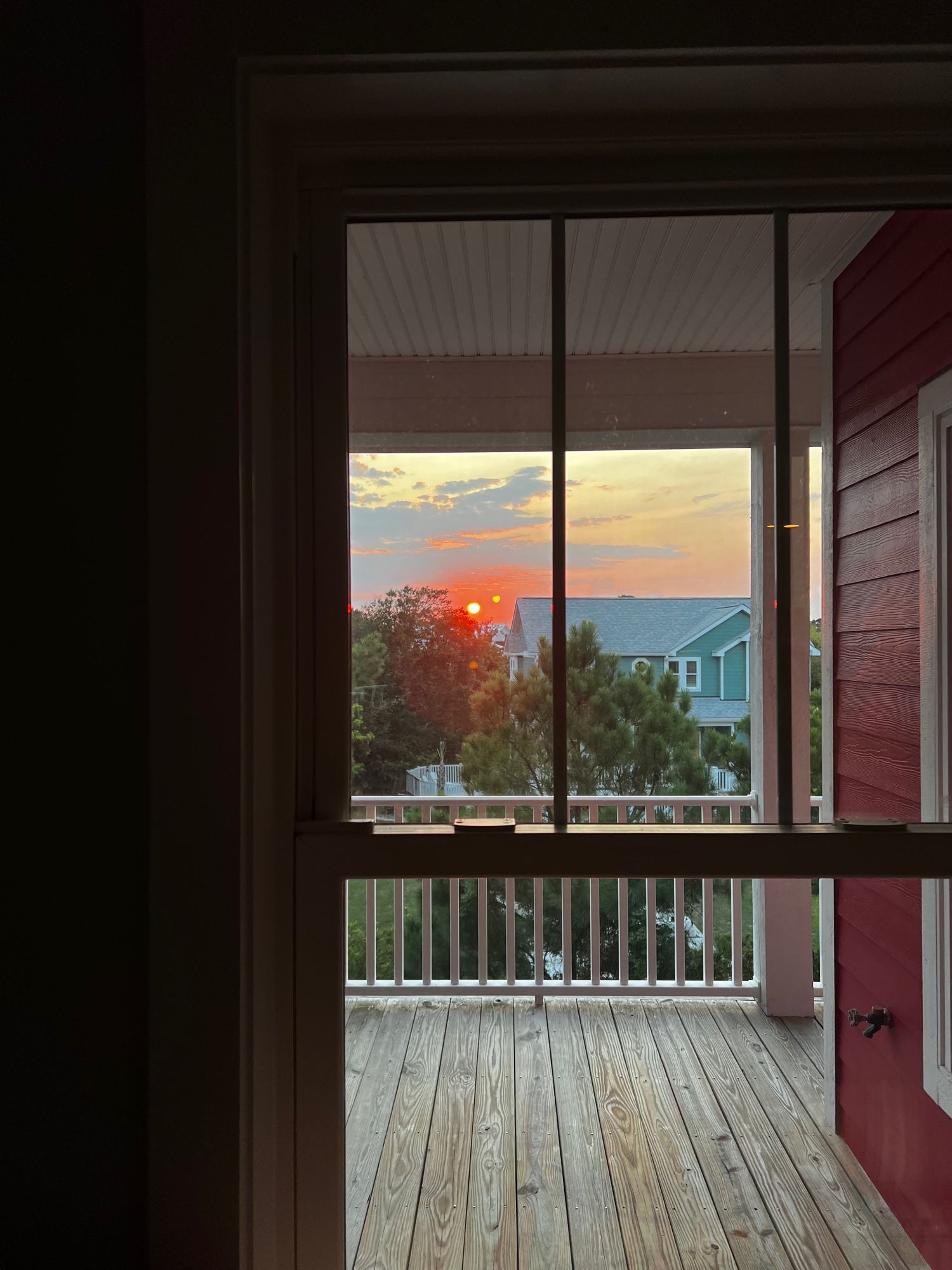 photo of a sunset over a deck through a window