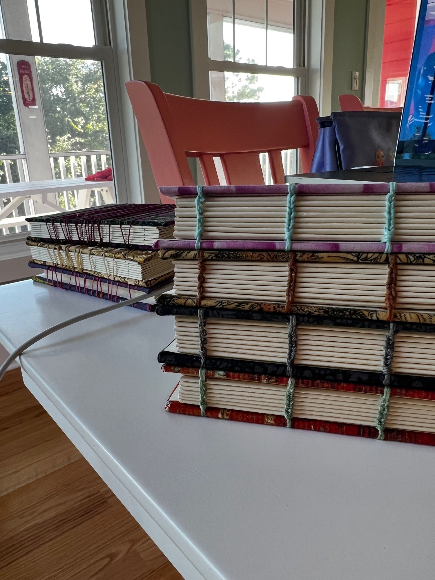 four freshly bound coptic stitch books with three in-progress coptic stitch books in the background