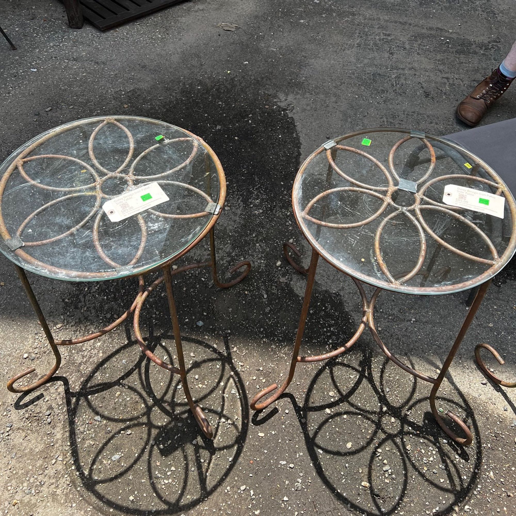 two small round glass top tables with iron flower designs visible through the glass