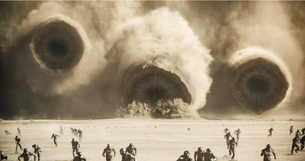 Three sand worms stream towards the viewer as small humanoids run in front of them.