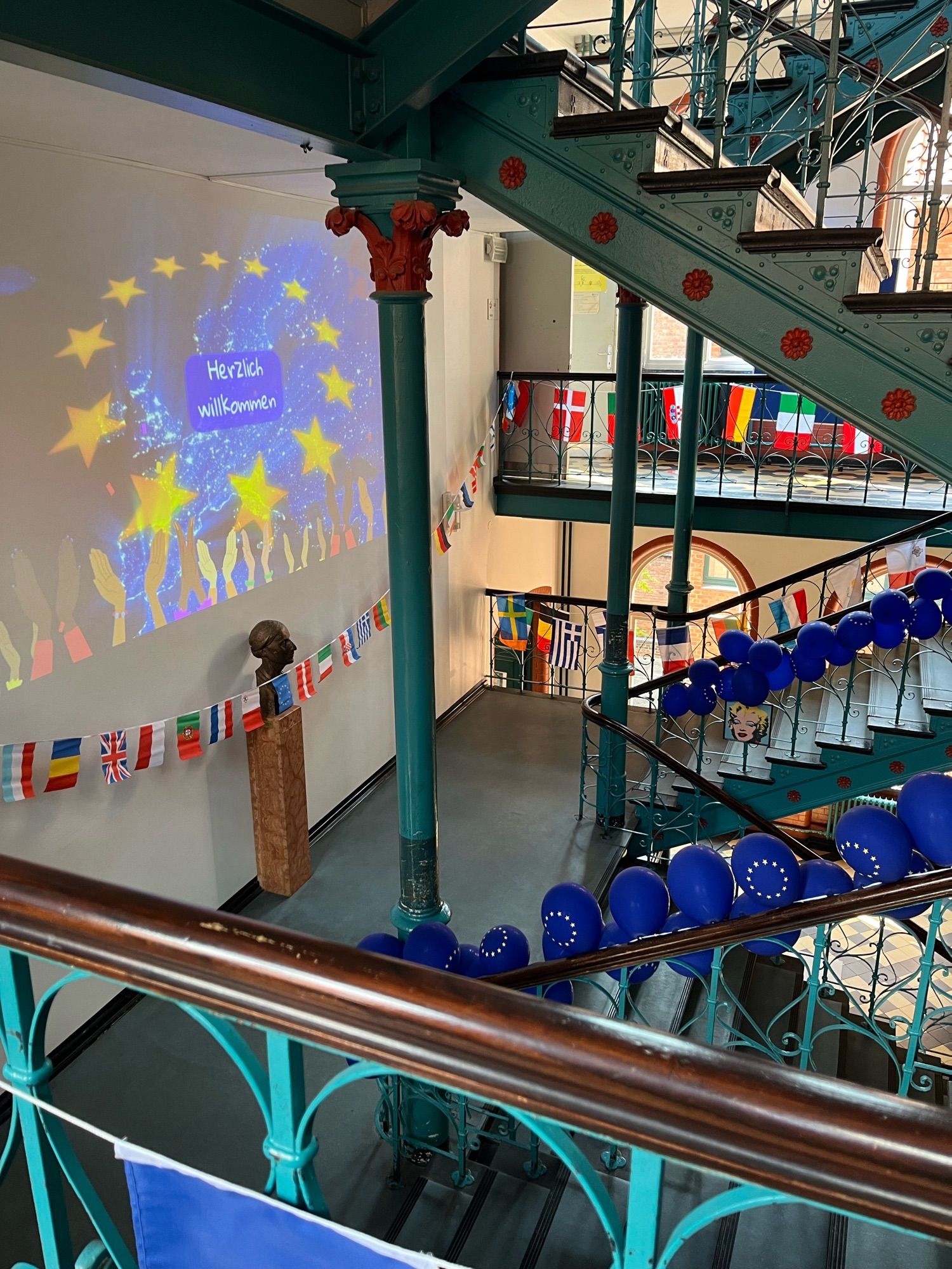 Blick in ein Treppenhaus, das mit Europa-Ballons geschmückt ist, per Projektion werden im Aufgang die Gäste der Veranstaltung begrüßt.