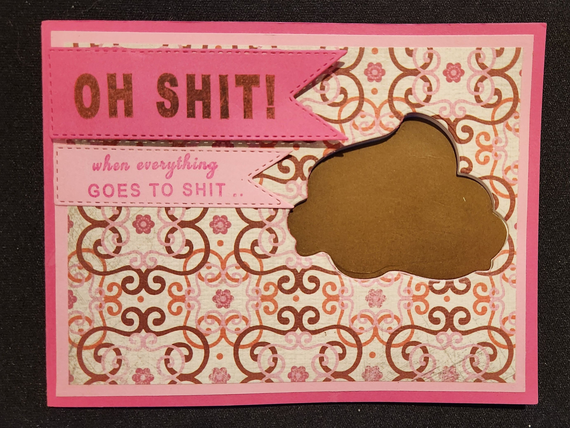 A handmade card in landscape orientation: the card base is hot pink. The front panel, with a ⅛" pale pink border on all sides, is a patterned background of pale pink and brown filigree and fuchsia flowers on ivory.

Visible through a cutout on the right side of the card is pile of brown "poop".

There are two penants on the front of the card. Stamped in brown ink on the larger, hot pink penant is "OH SHIT!" in all caps. Stamped in hot pink ink on the smaller pale pink penant is "When everything goes to shit..."