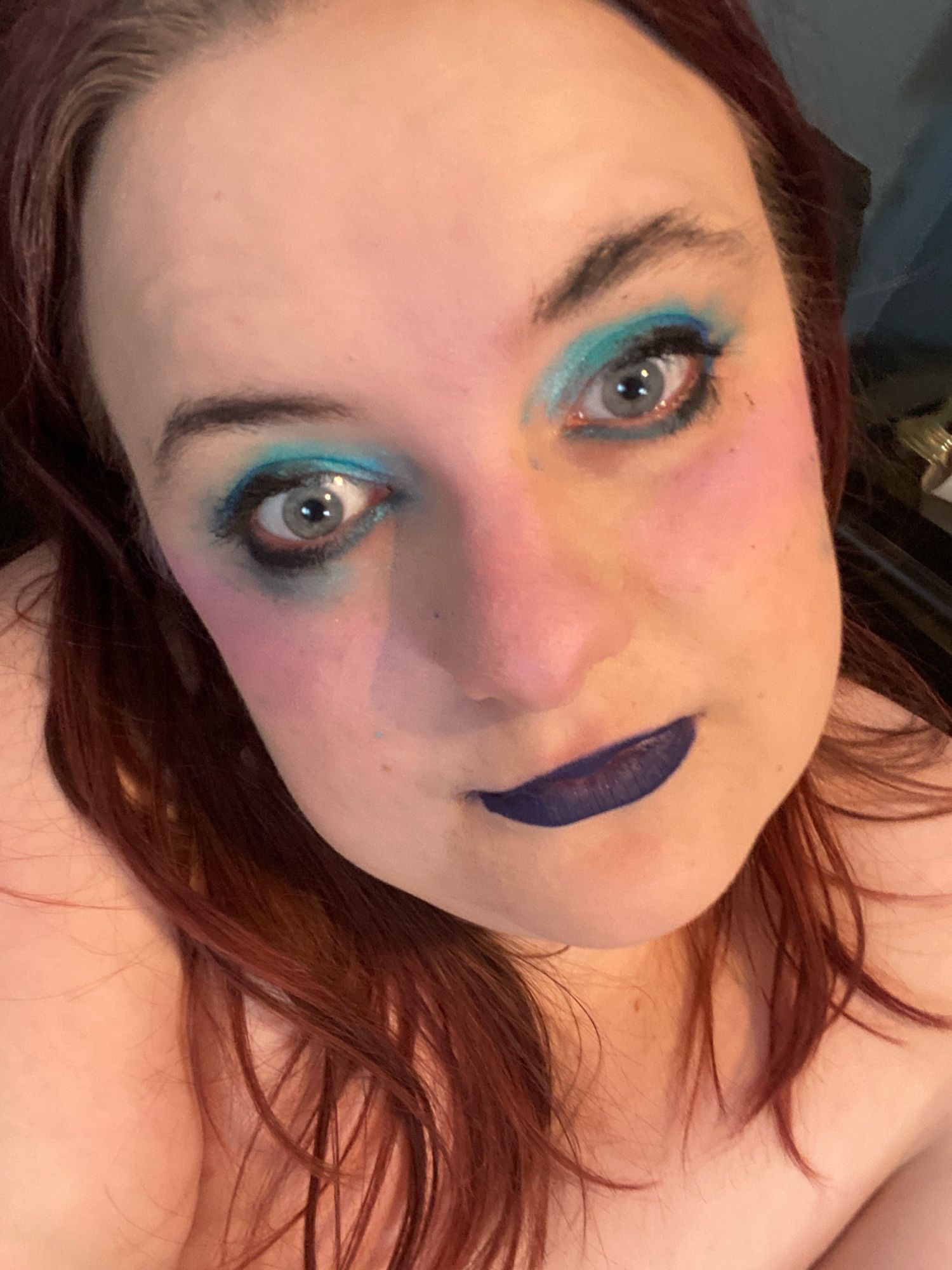 high angle selfie of sinead with same hair, dark purple lips, and kinda sloppy baby blue eye makeup. 