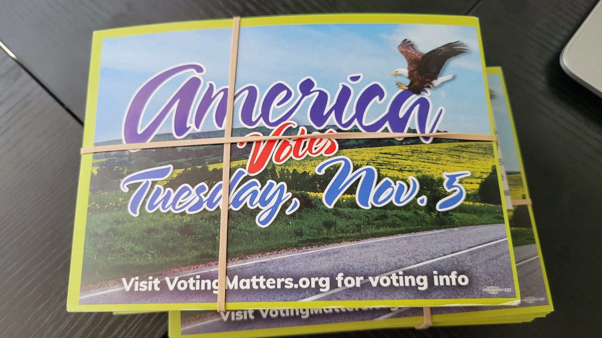 A stack of postcards that read "America votes Tuesday, Nov. 5" with a field of wildflowers in the background and a bald eagle swooping in from the top.