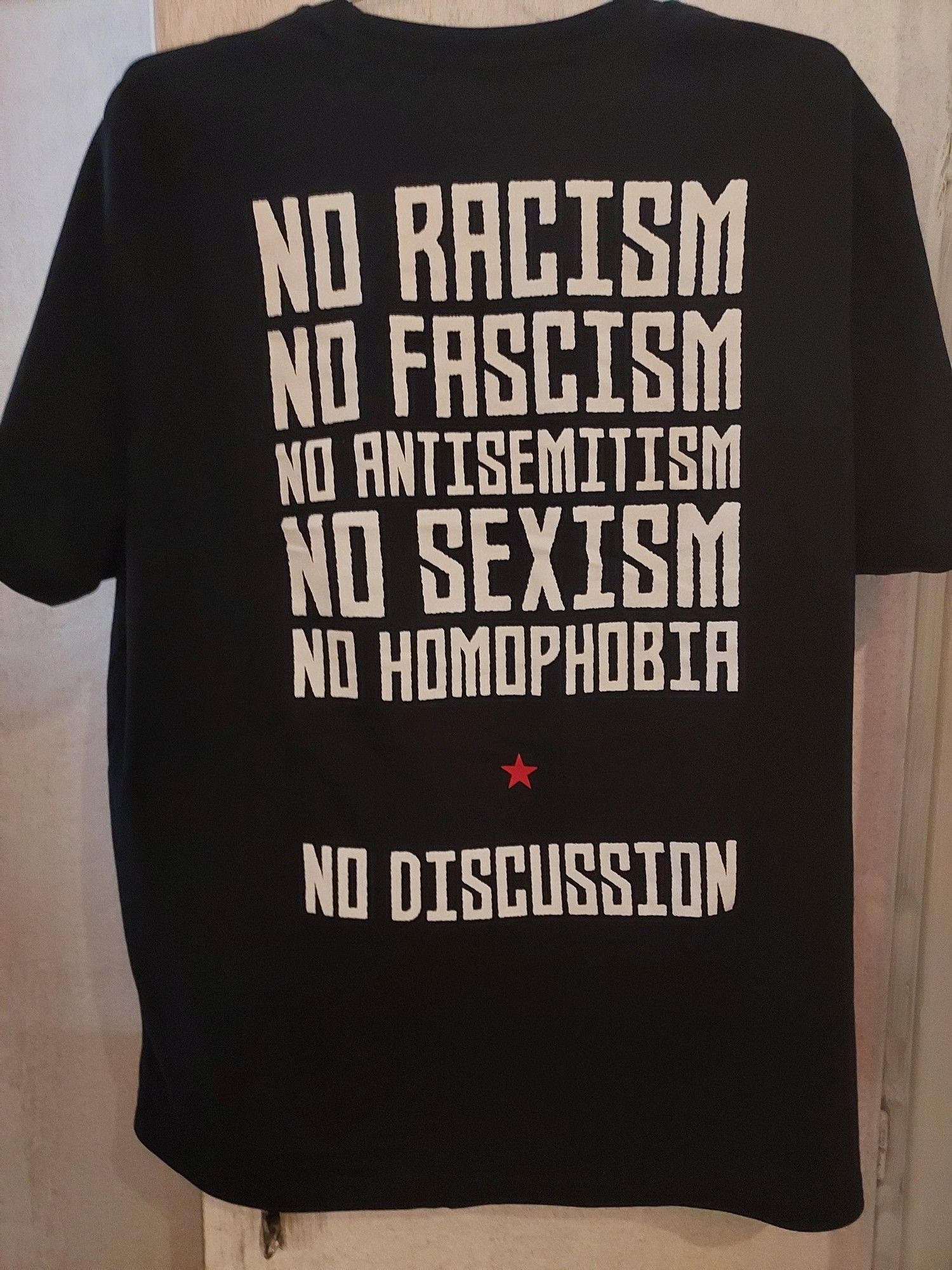 Schwarzes T-Shirt mit dem Aufdruck NO RACISM,NOFASCISM,NO ANTISEMITISM,NO SEXISM,NO HOMOHOBIA, NO DISCUSSSION