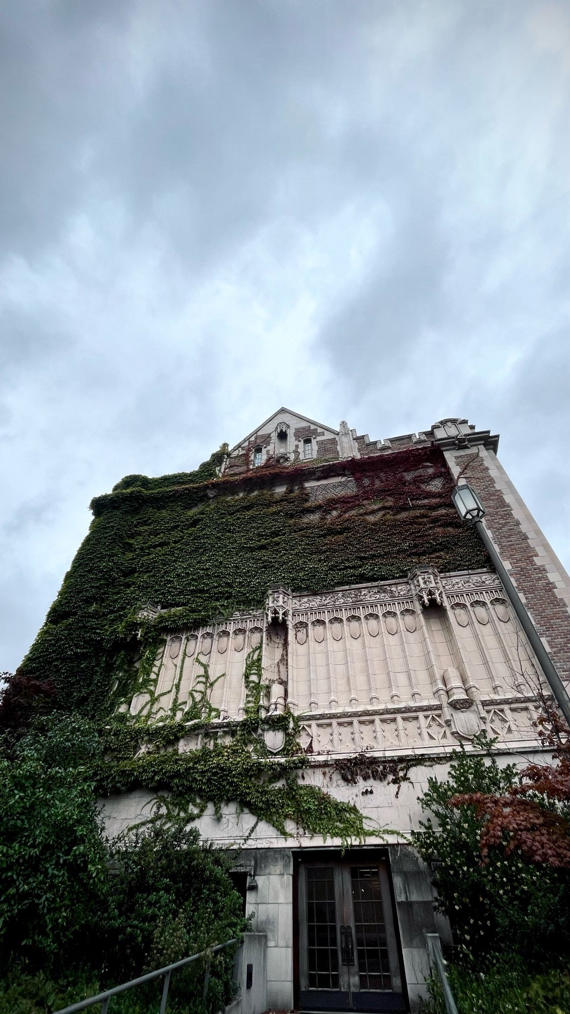 Picture of a gothic-style university building with ivies on the facade. The sky is overcast.