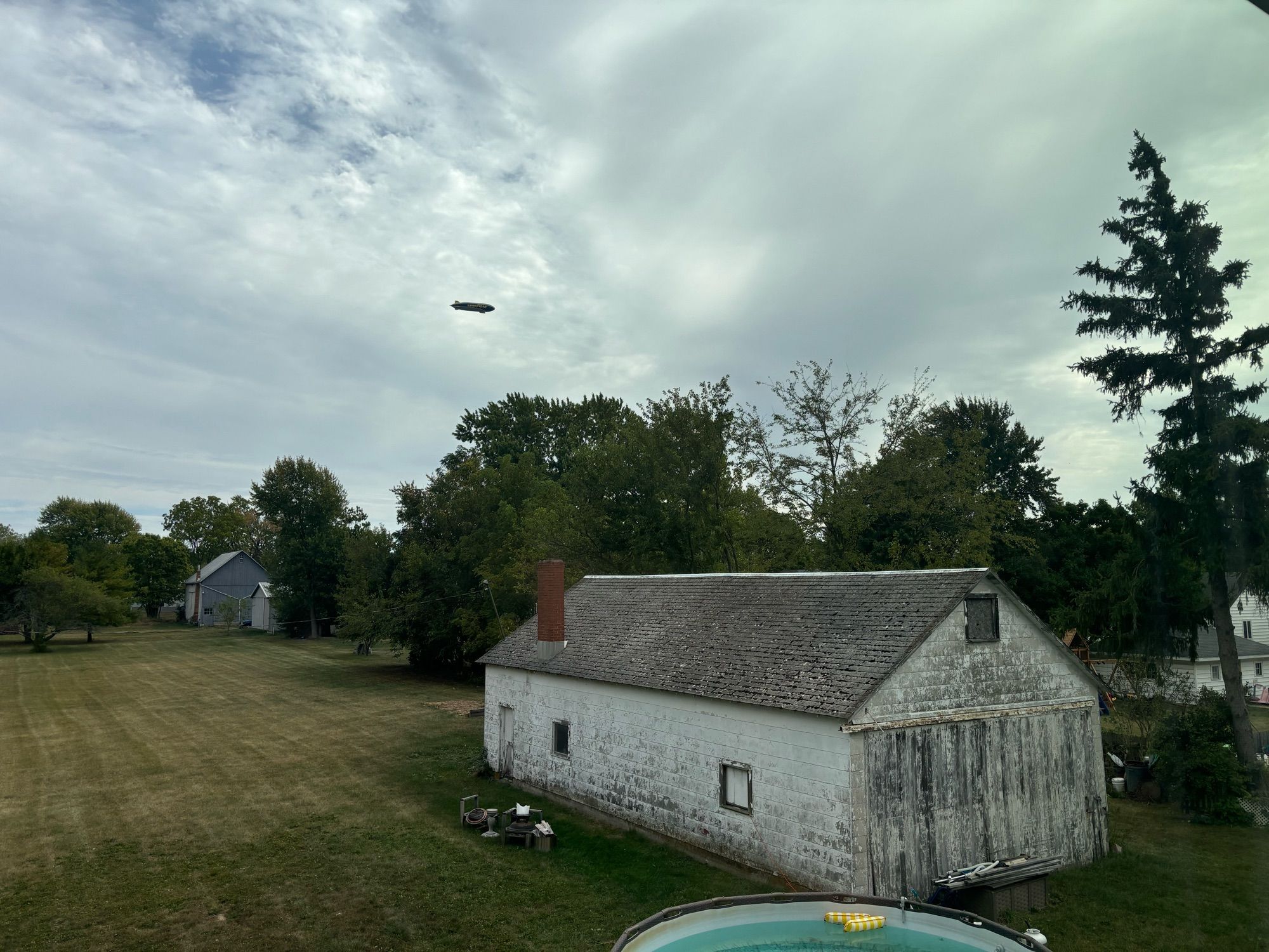 Goodyear blimp over an old white barn