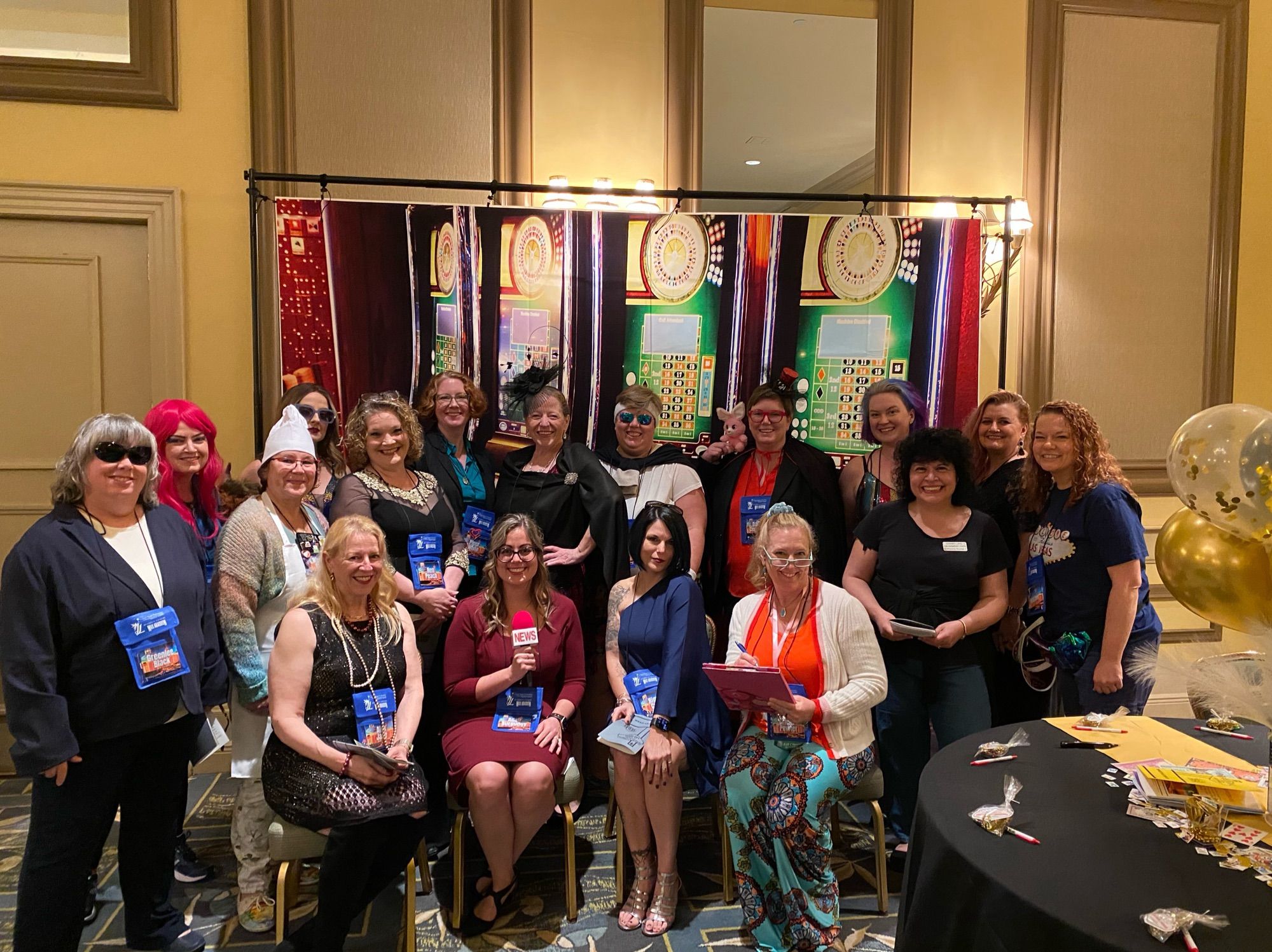 Group photo of 17 authors who played characters at our murder mystery event night at the Coastal Magic Book Conference in Daytona Beach Florida on Friday February 23 2024. Group is dressed up in character standing in front of a casino themed backdrop