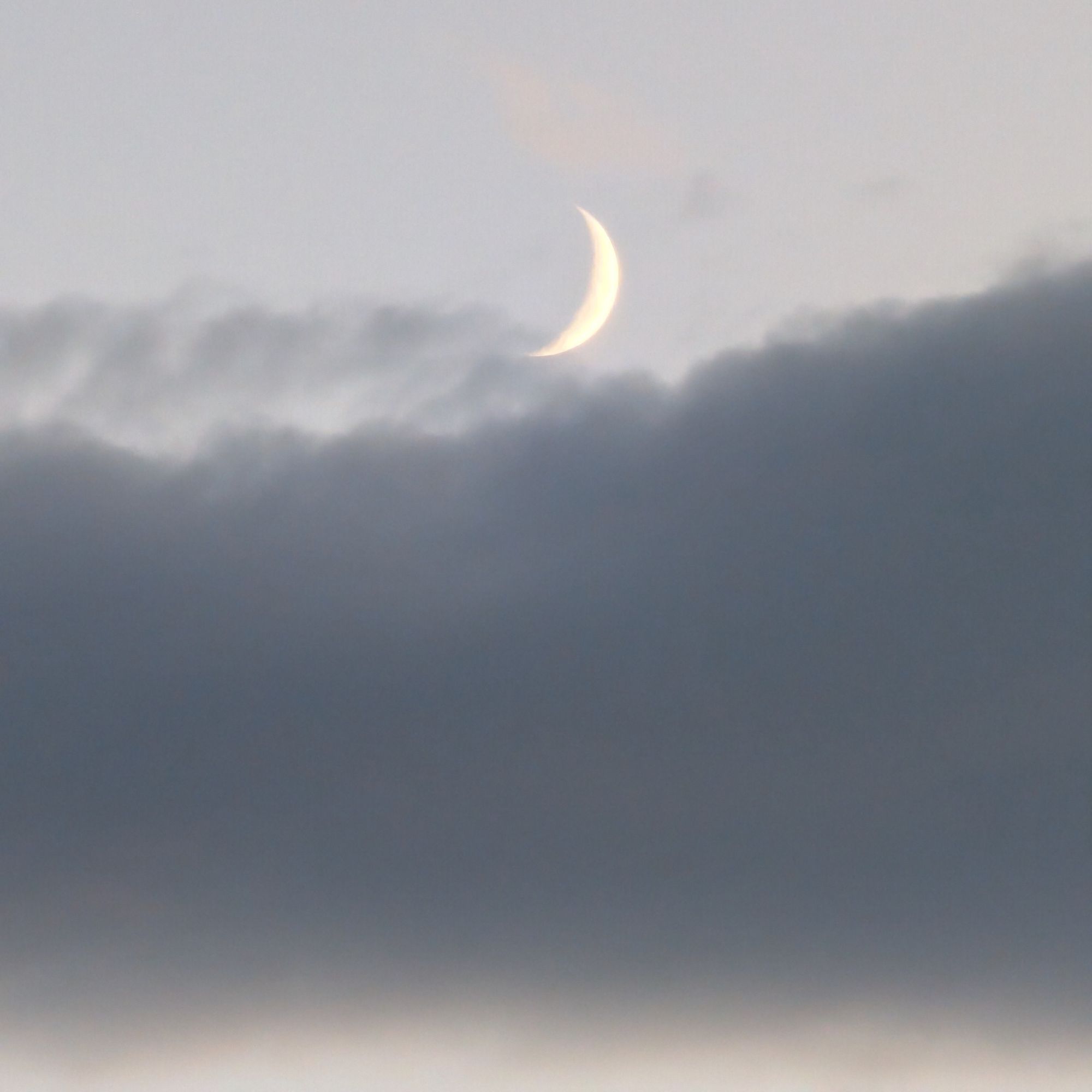 The beautiful crescent moon, glowing in the sunset, was hidden by clouds in a moment