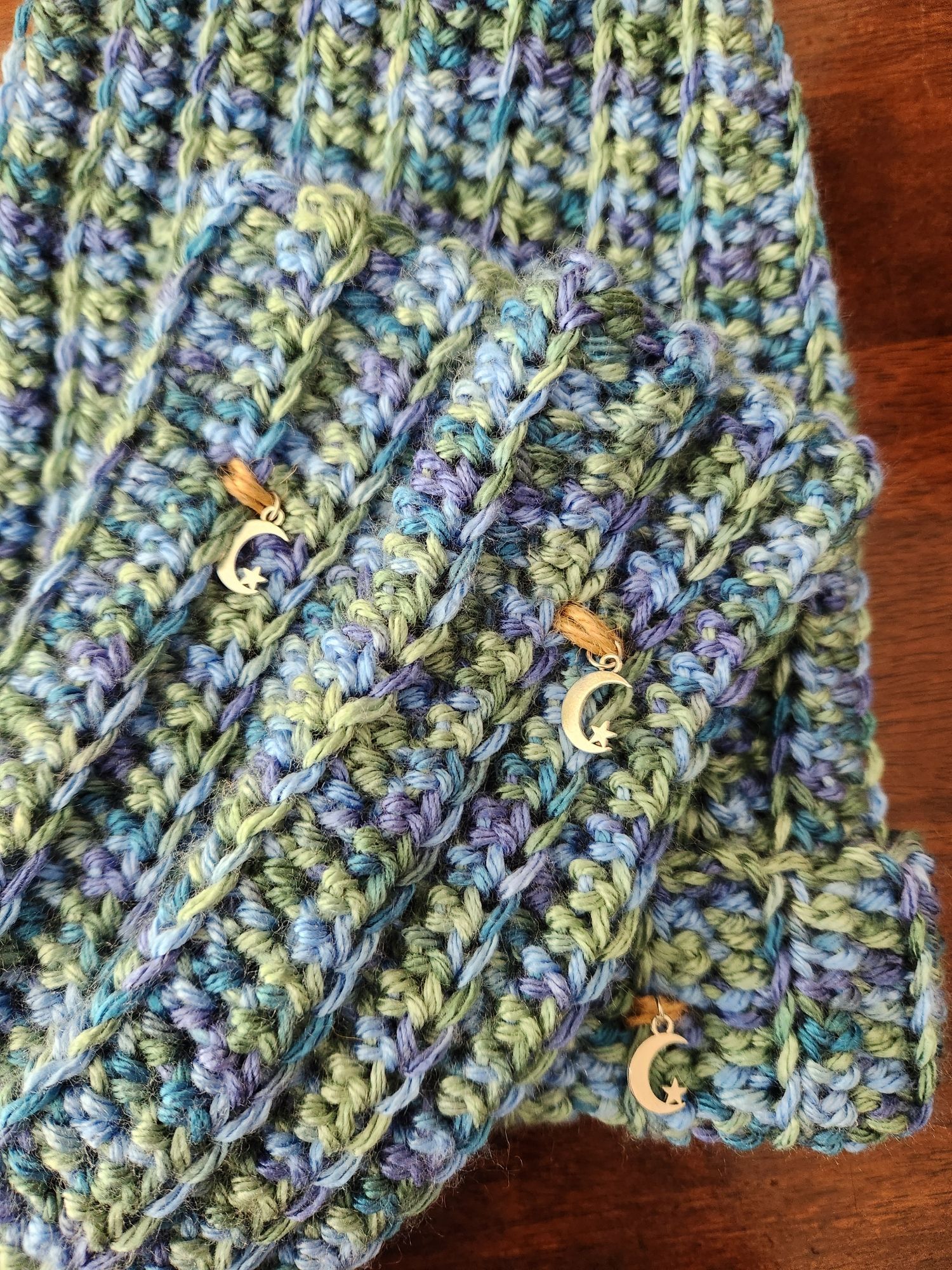 closeup of green & blue varigated beanie & armwarmers; moon & star charms tied on with hemp