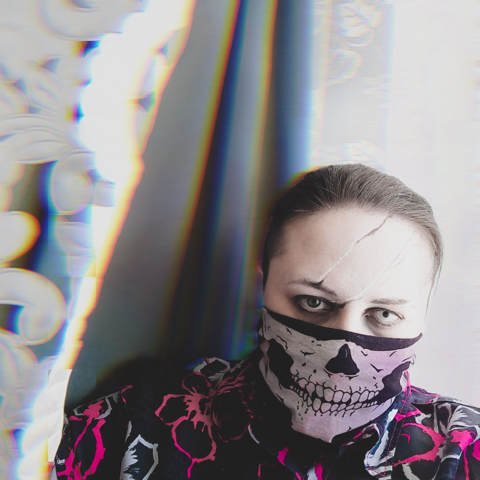 A guy in claw-scars make-up (black and white, nothing triggering), half-face tube mask with fanged skull print (no association to any bigoted fools), hawaiian print shirt in white and hot pink.