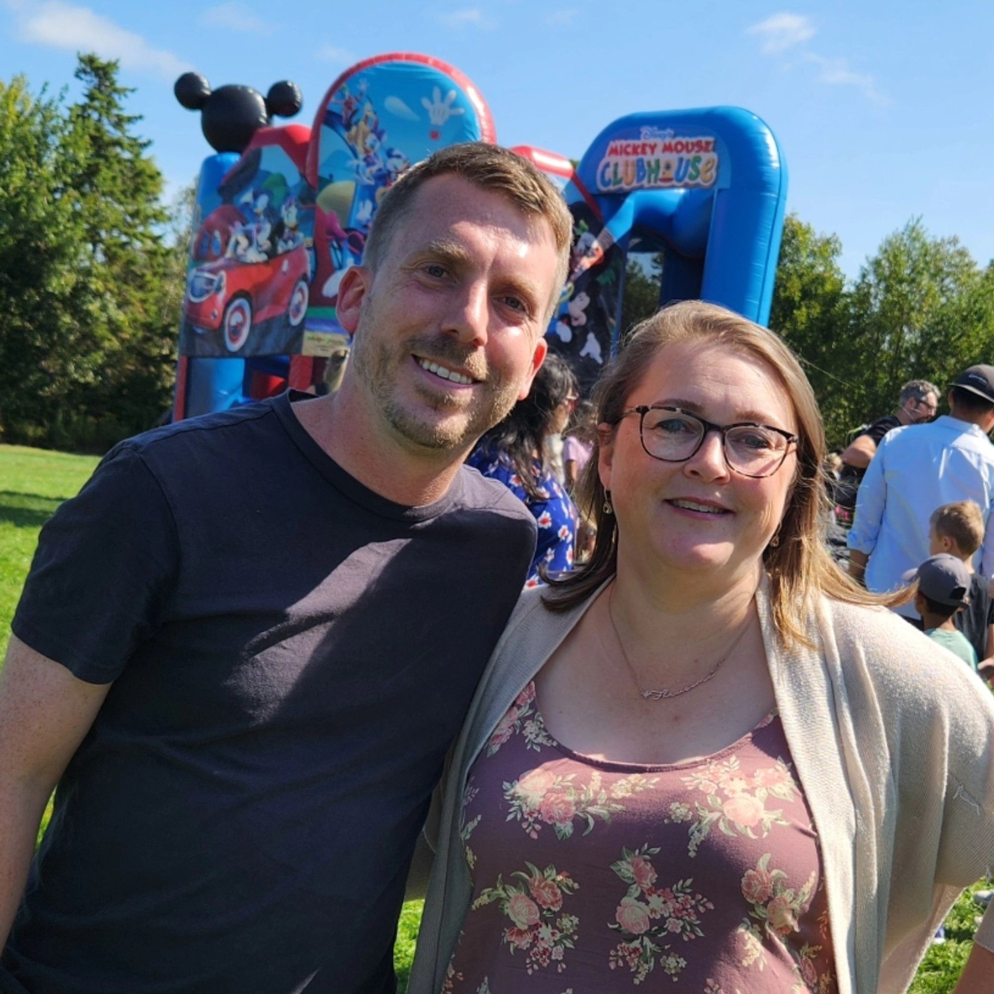 Anita and Braeden standing in front of a blow up boncy castle that is Mickey Mouse themed.