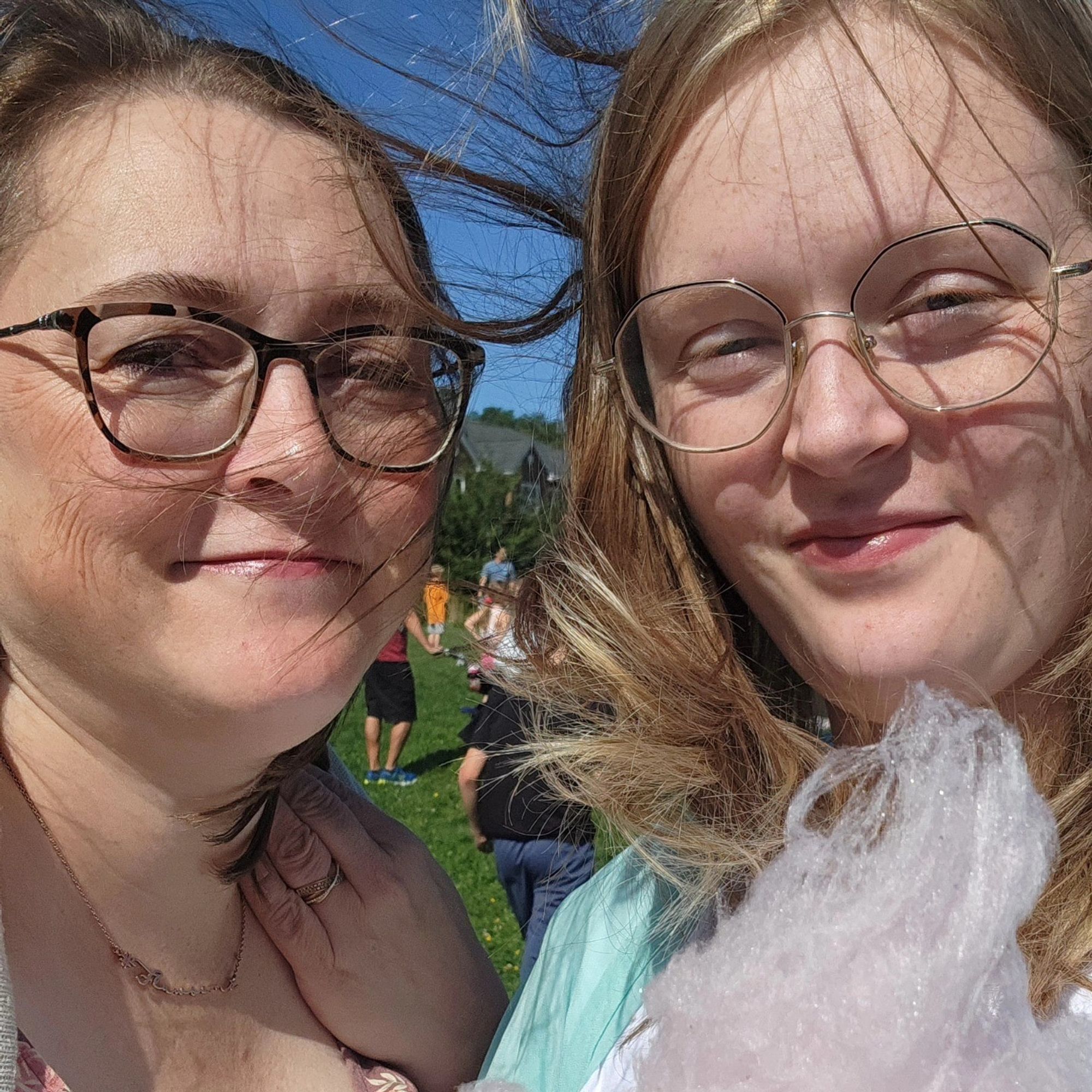 Anita and Campaign Assistant Elizabeth trying to eat pink cotton candy on a stick while their long brown hair flies in the wind.